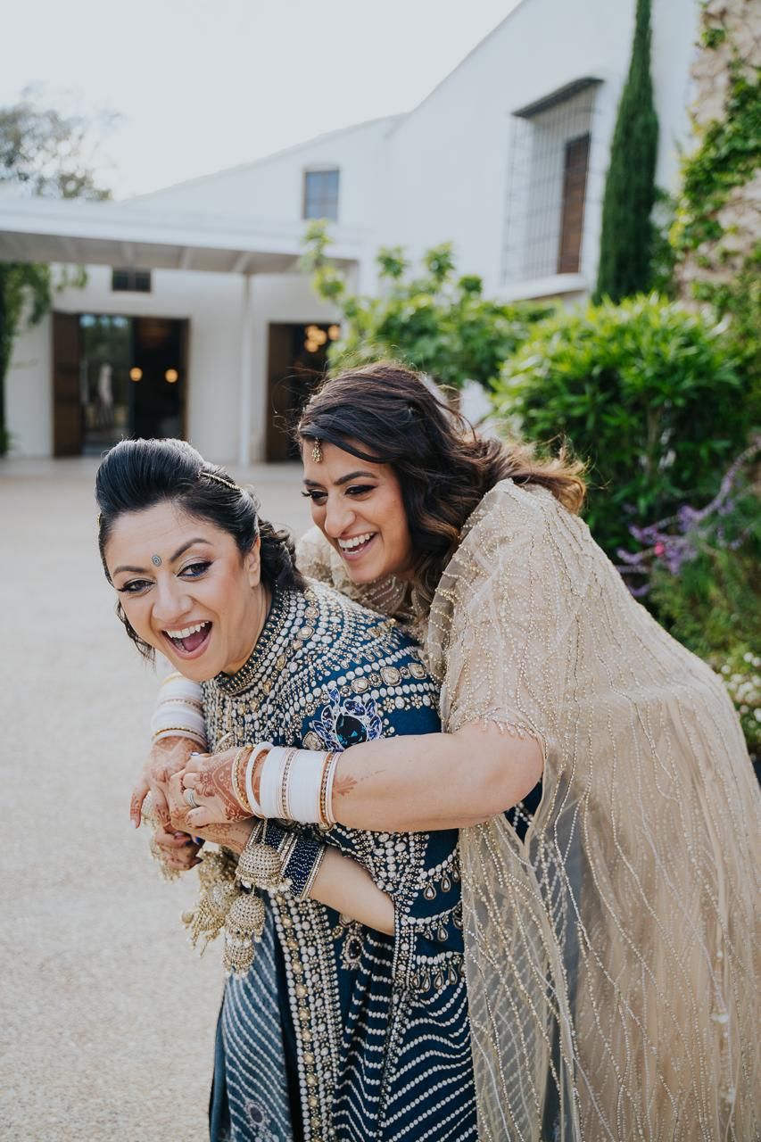 Indian bride and bride in traditional attire with professional makeup and hair styling. Luxury ethnic wedding beauty services in Spain.