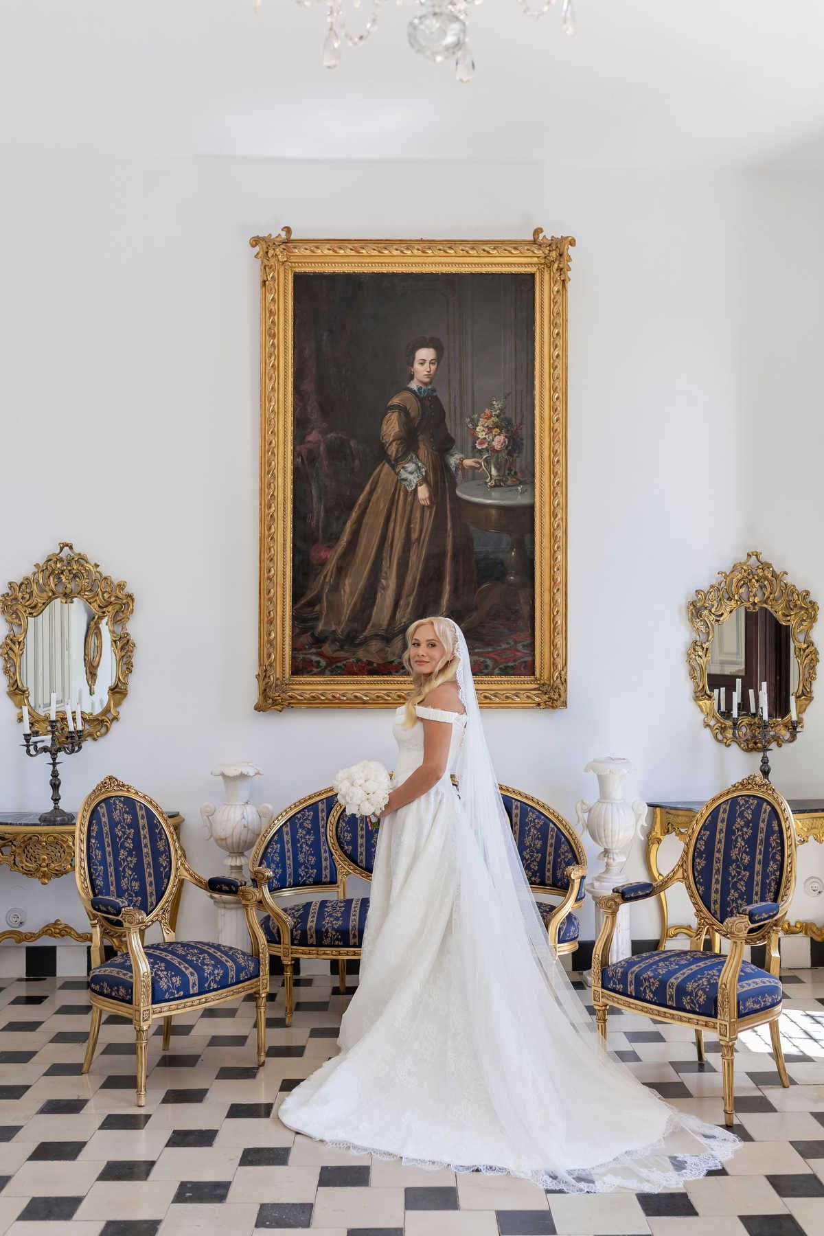 Breathtaking bride with a delicate veil and soft Hollywood waves posing by the antique doors of Finca Marqués de Montemolar.