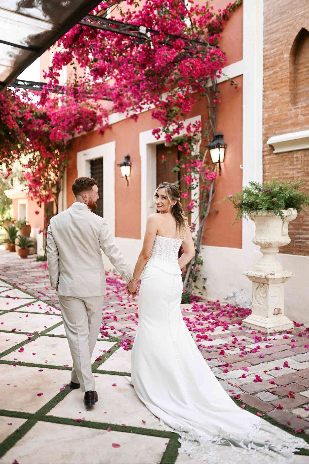 Happy newlyweds walking past the Villa Delia facade. Flawless wedding makeup and hair look created by a beauty specialist in Valencia.