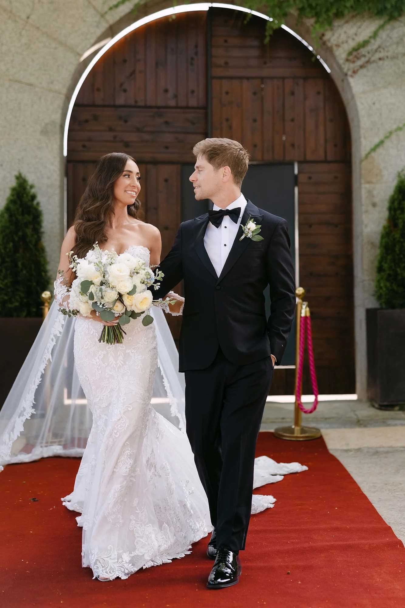 The bride and groom walking from the grand gates of the estate, capturing a high-fashion editorial wedding vibe.