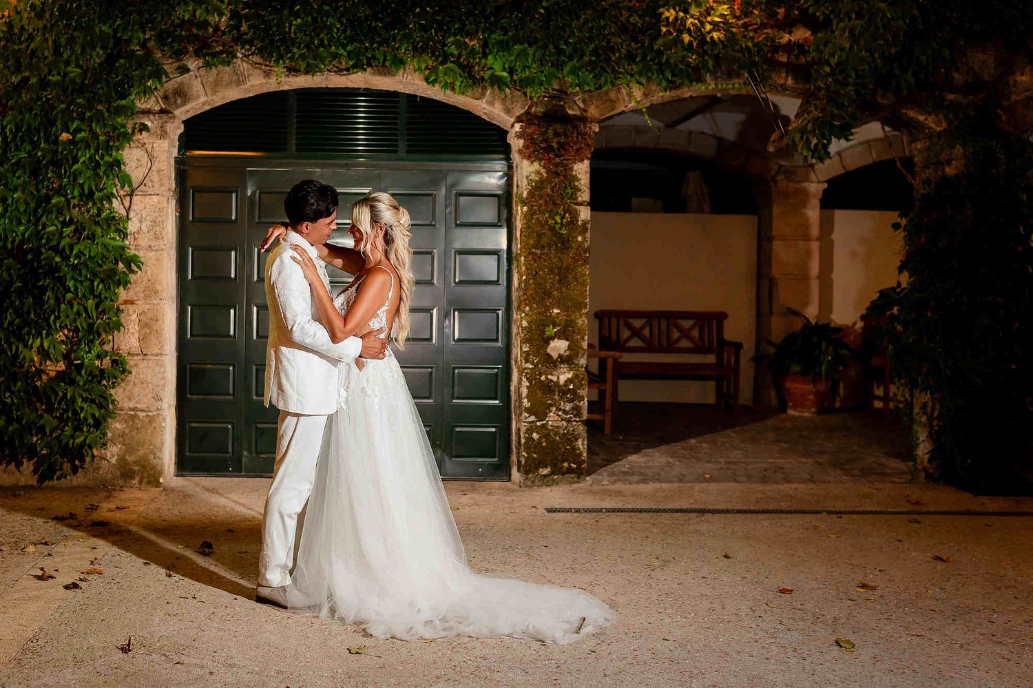 Wide shot of the groom kissing the bride amidst the lush Mediterranean greenery and gardens of the Casa Santonja estate.