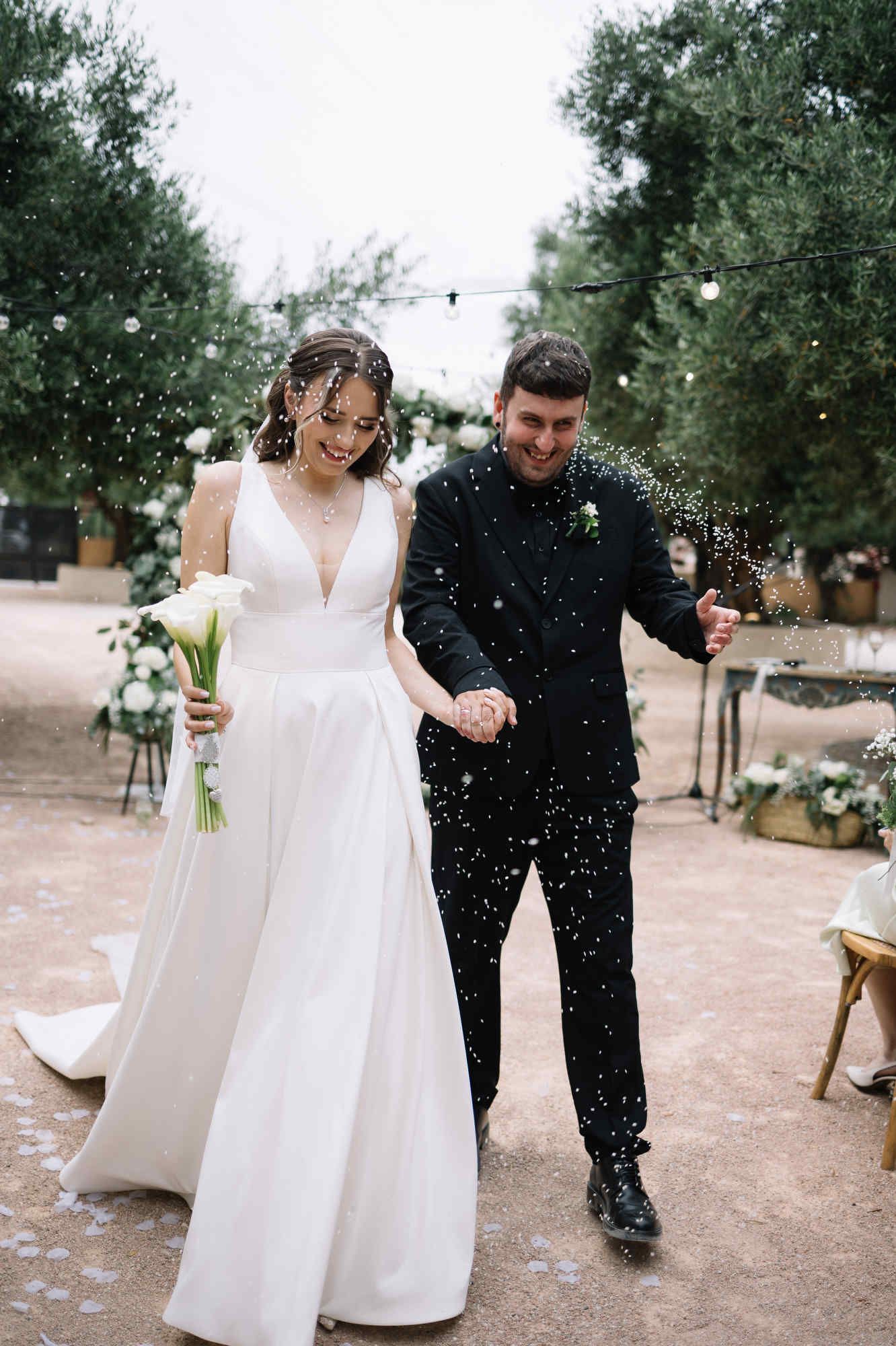 Bride and groom being showered with grain in a traditional wedding exit after the ceremony at Alqueria del Xúquer, Valencia.