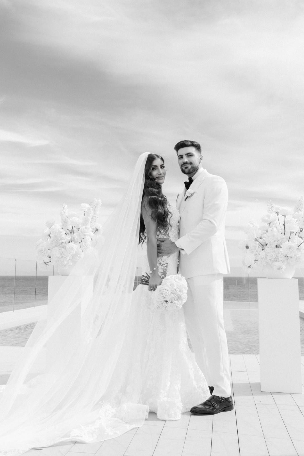 The bride and groom posing at their ME Ibiza wedding ceremony with stunning Mediterranean sea view and flawless professional bridal styling