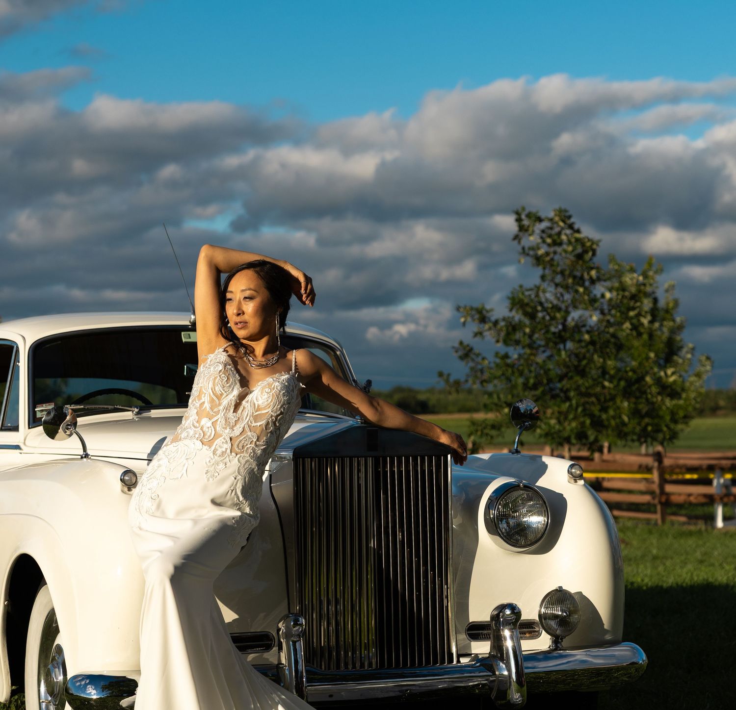Classic white Rolls Royce photographed in outdoor setting with dramatic sky.