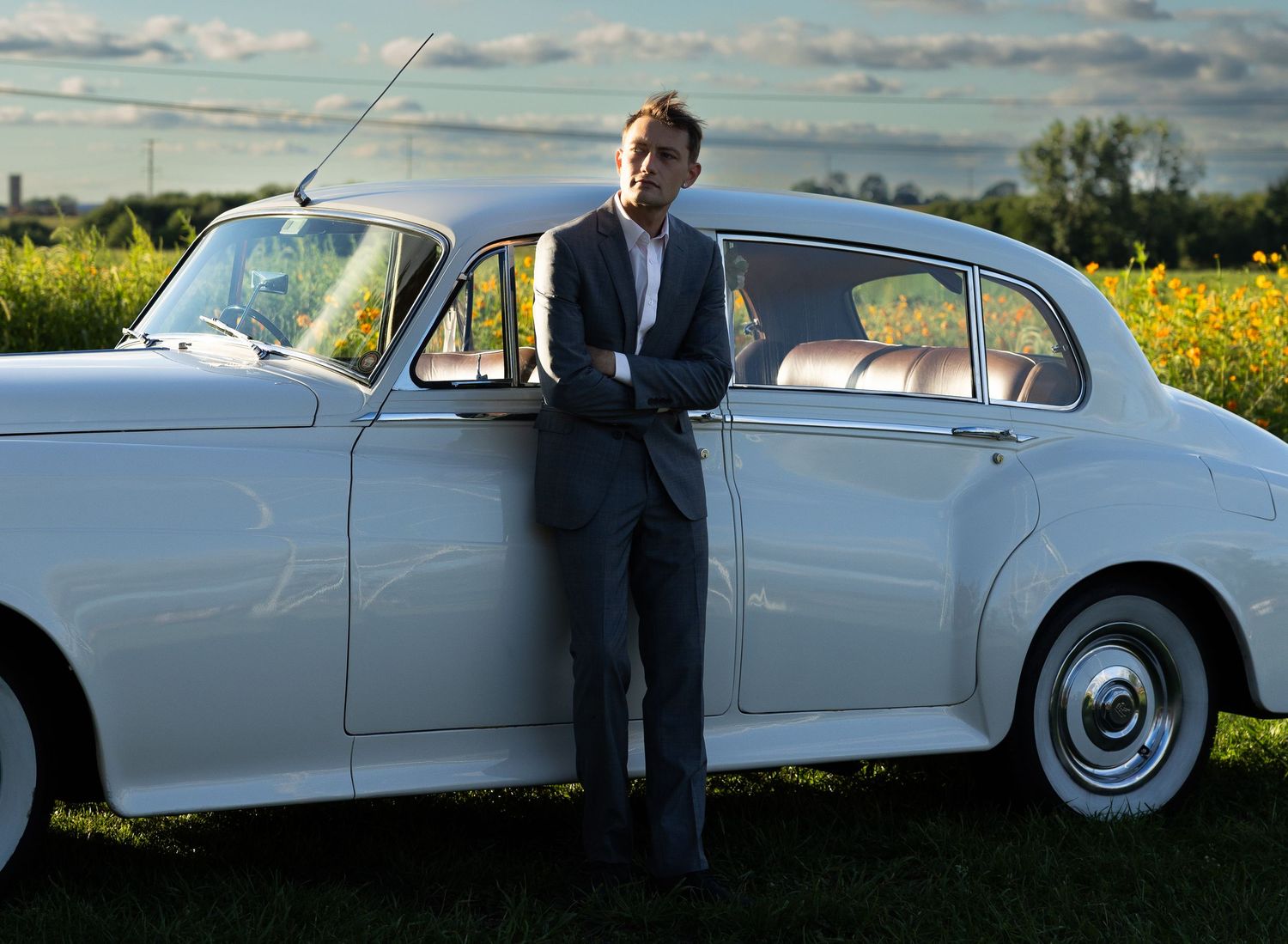 Classic white car photoshoot in a countryside setting with yellow wildflowers.