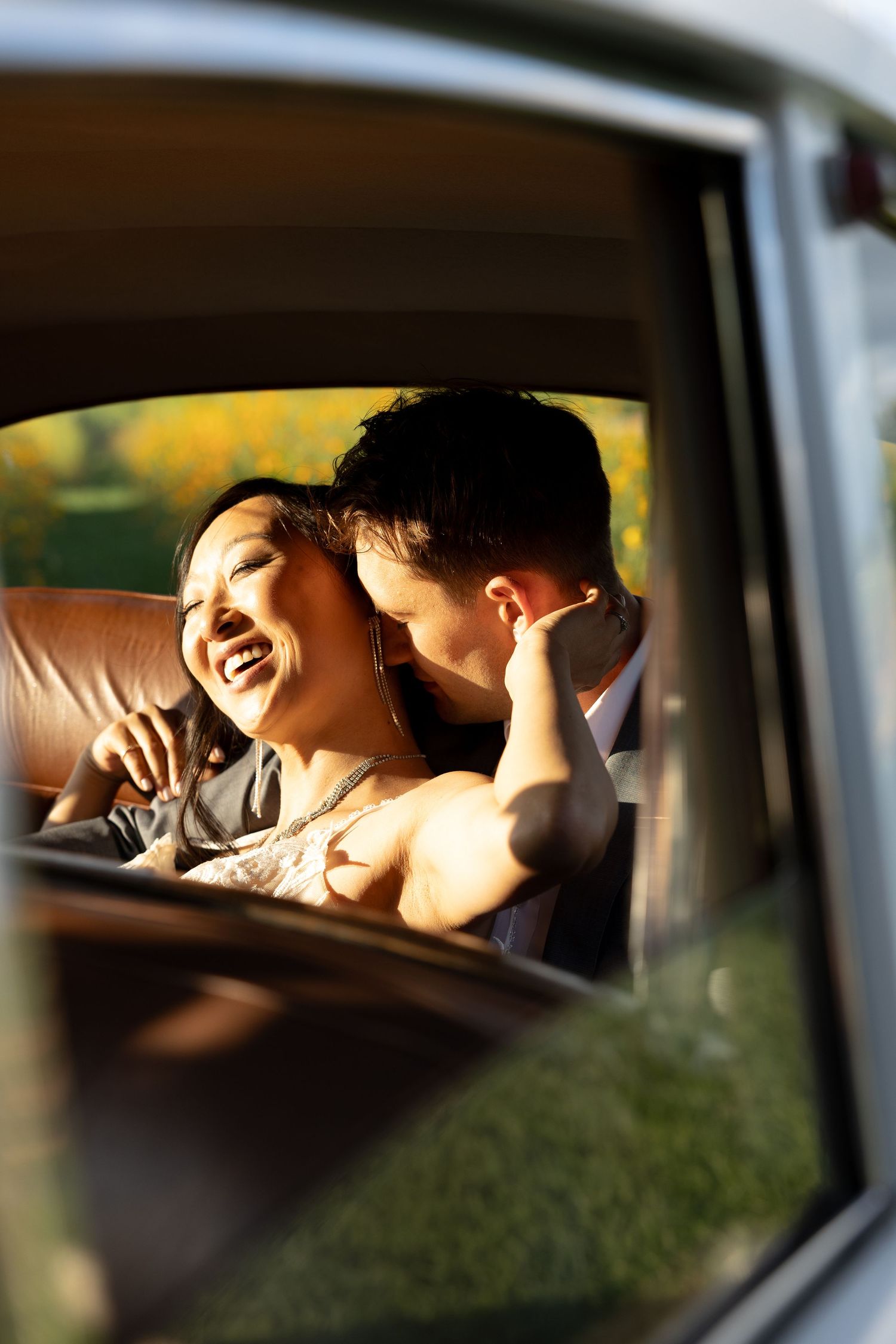 A person relaxes in the backseat of a car on a sunny day, viewed through the car window.