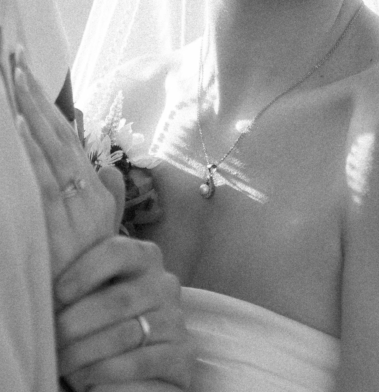 Close-up details of wedding attire in soft black and white lighting.