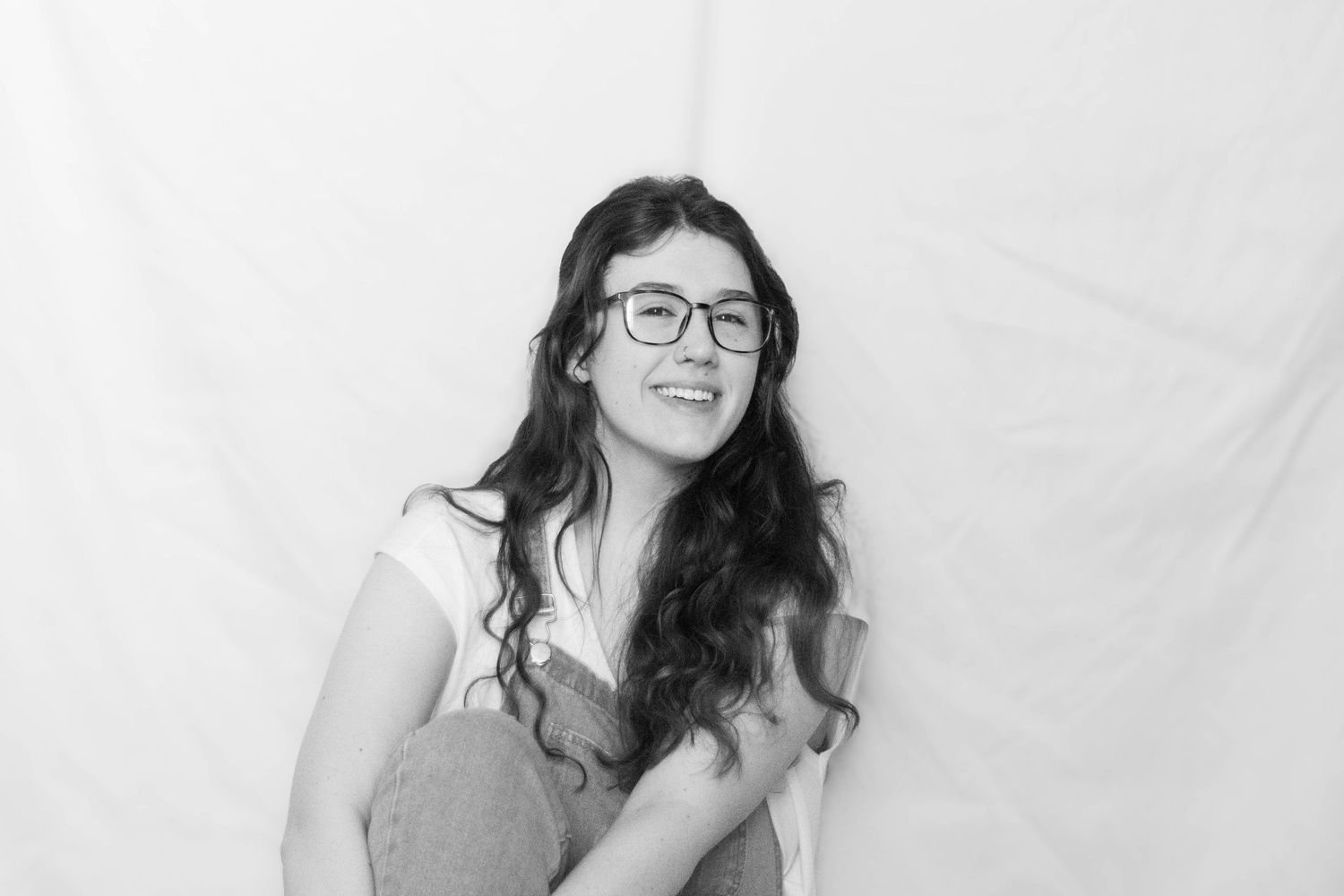 A sequence of black and white portraits featuring someone with glasses holding a vintage camera.