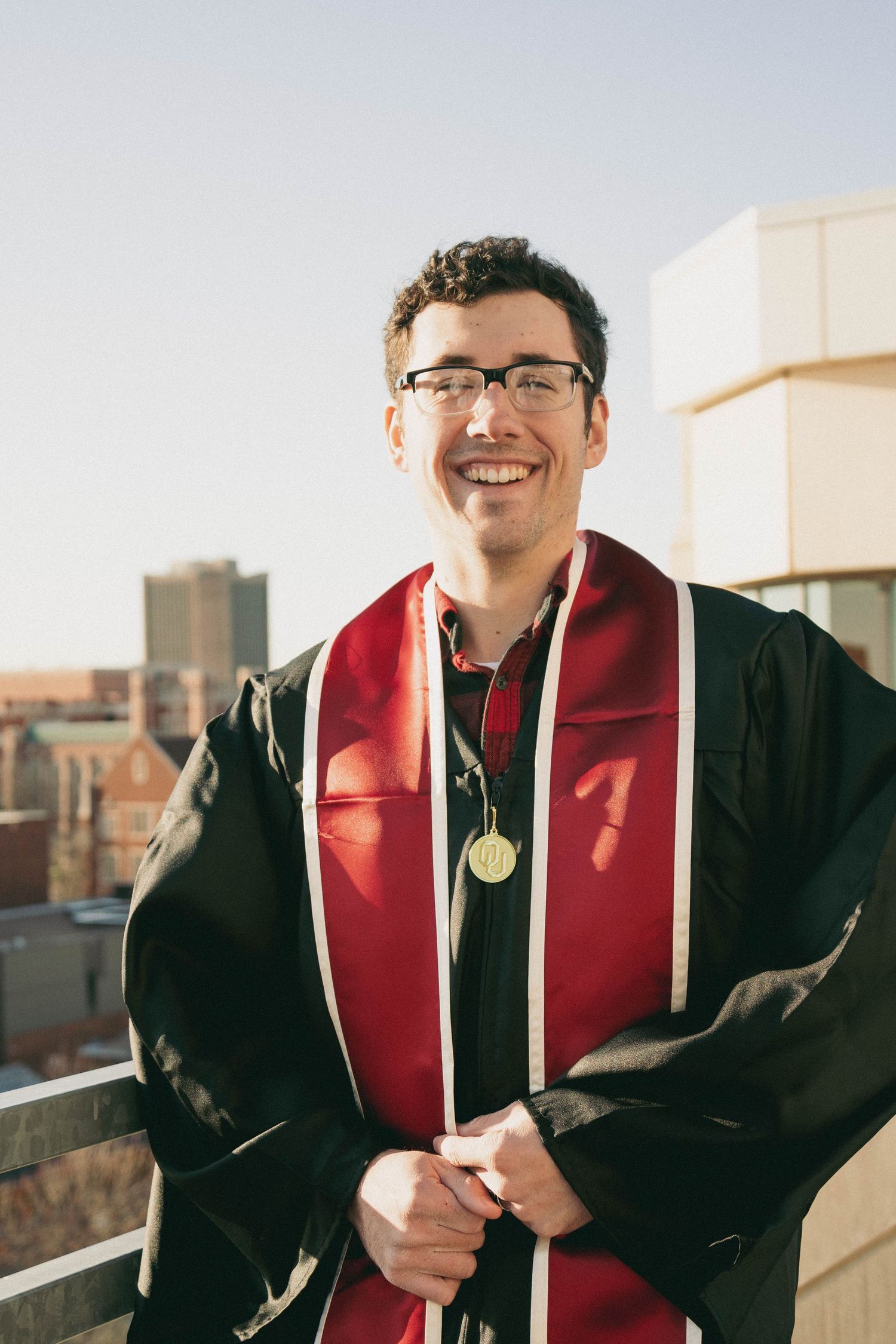 Graduate in cap and gown smiling outdoors on graduation day.