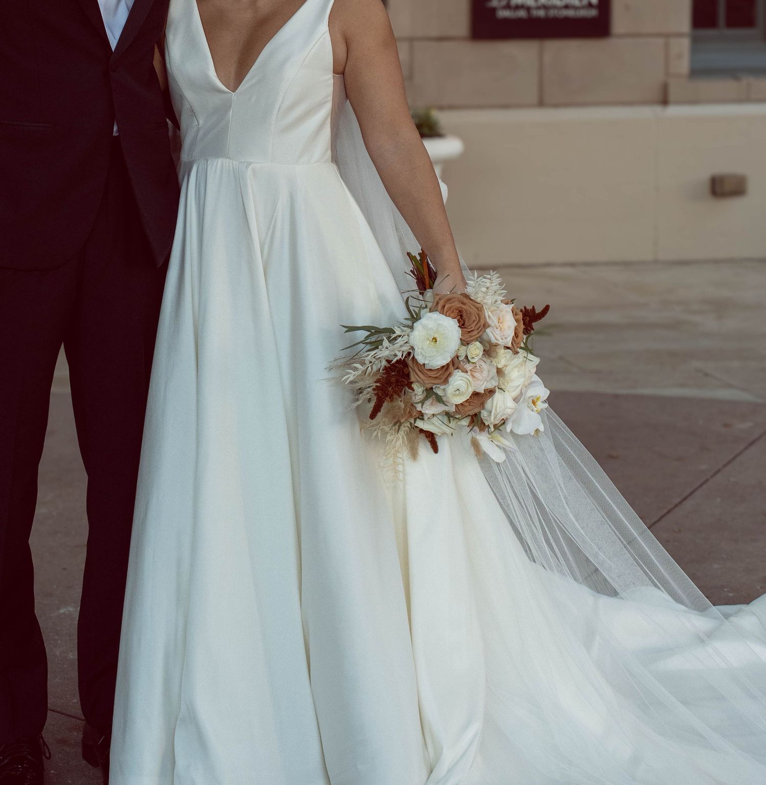 Elegant white wedding dress with flowing train photographed against stone architecture.