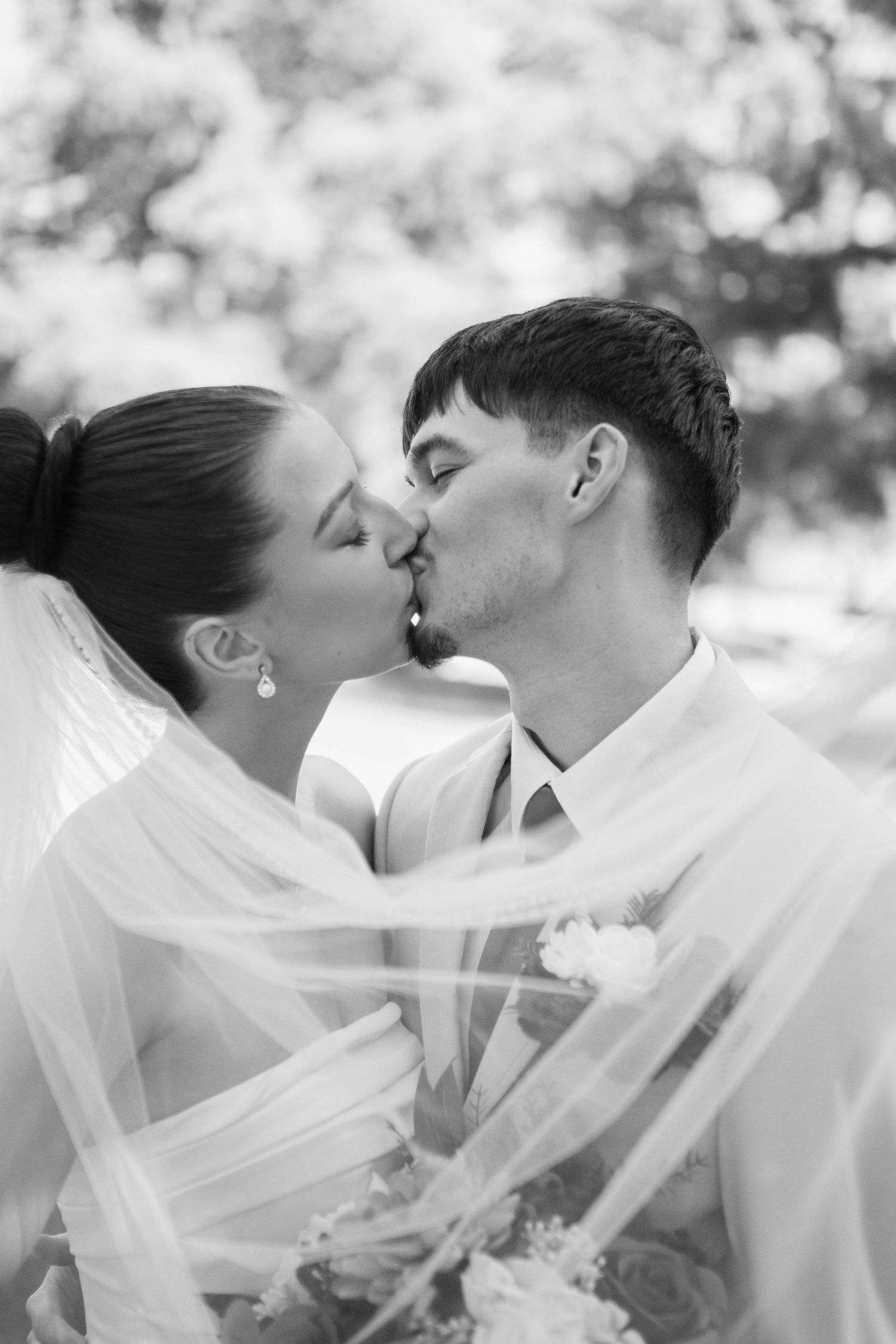 Intimate black and white portrait of a wedding couple sharing a romantic kiss.