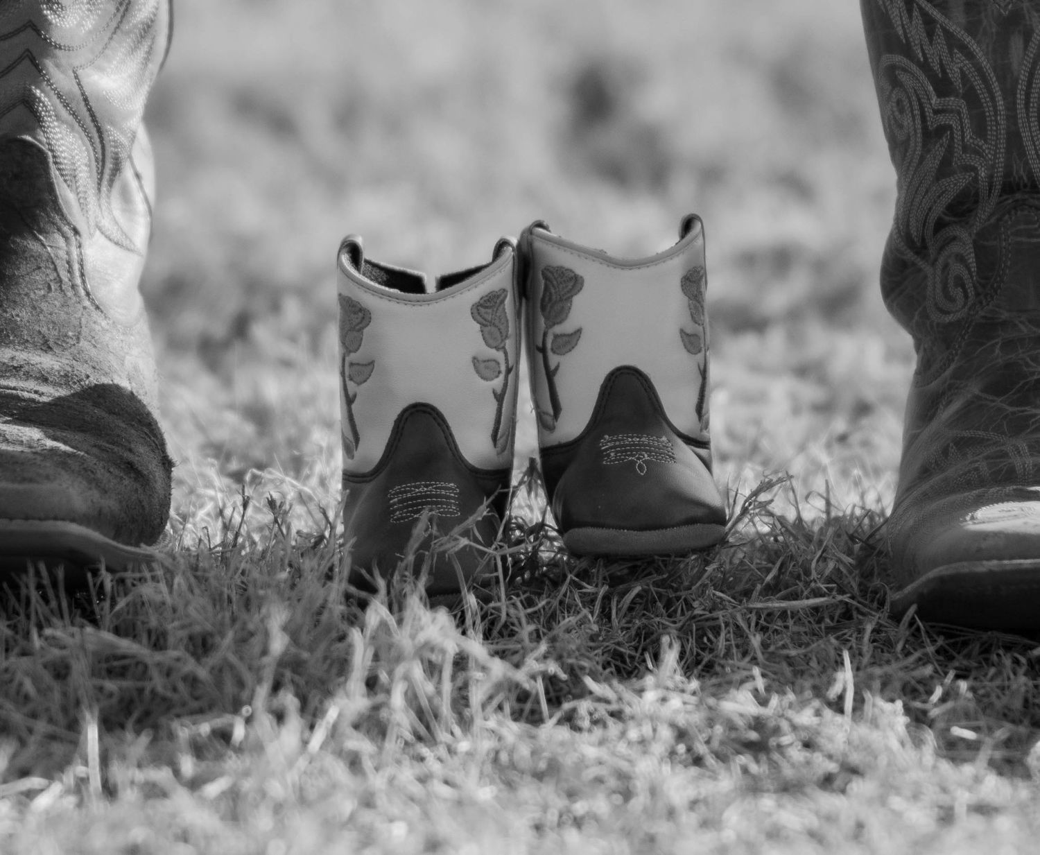 Boots of two people standing close together on grass.