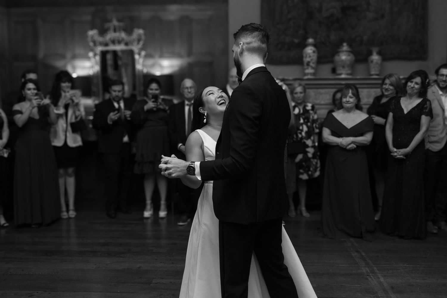 Wedding couple shares their first dance in black and white on a dimly lit dance floor.