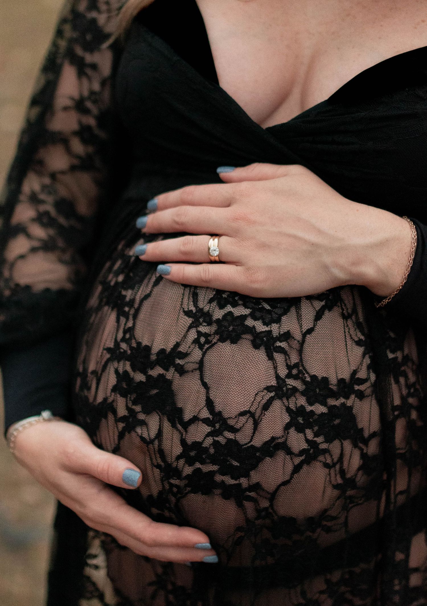 Close-up details of a black lace maternity dress with delicate floral patterns.