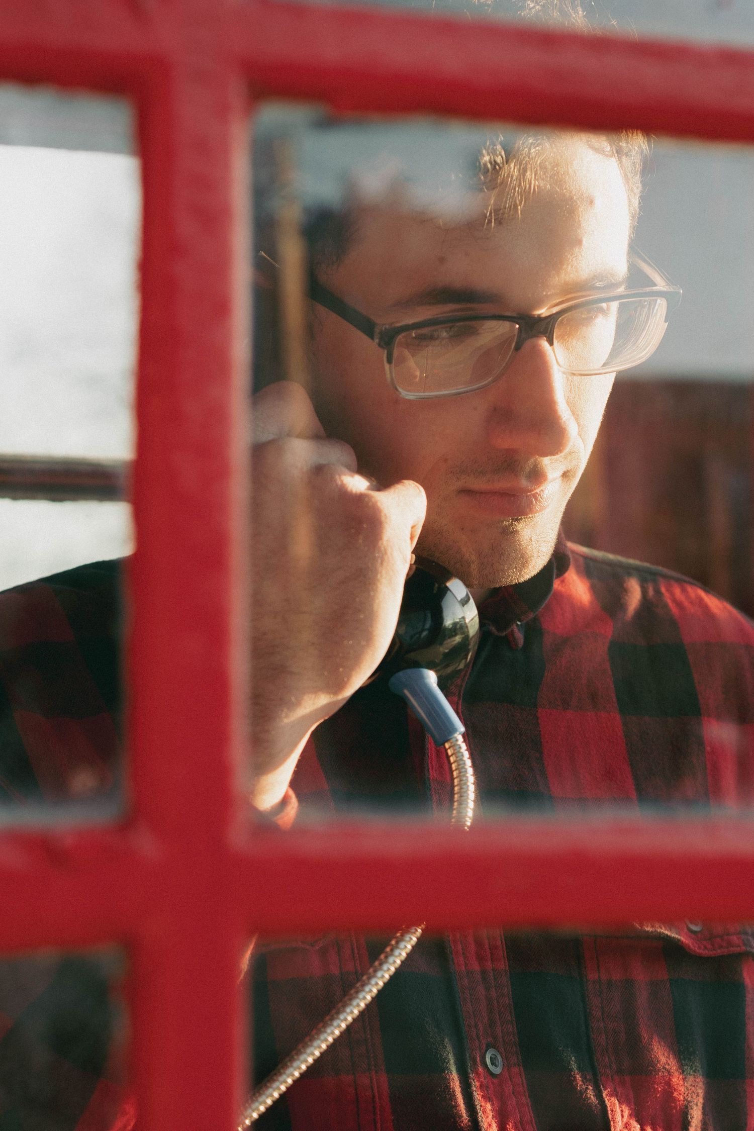 Close-up portrait through red window panes creating an artistic geometric composition.