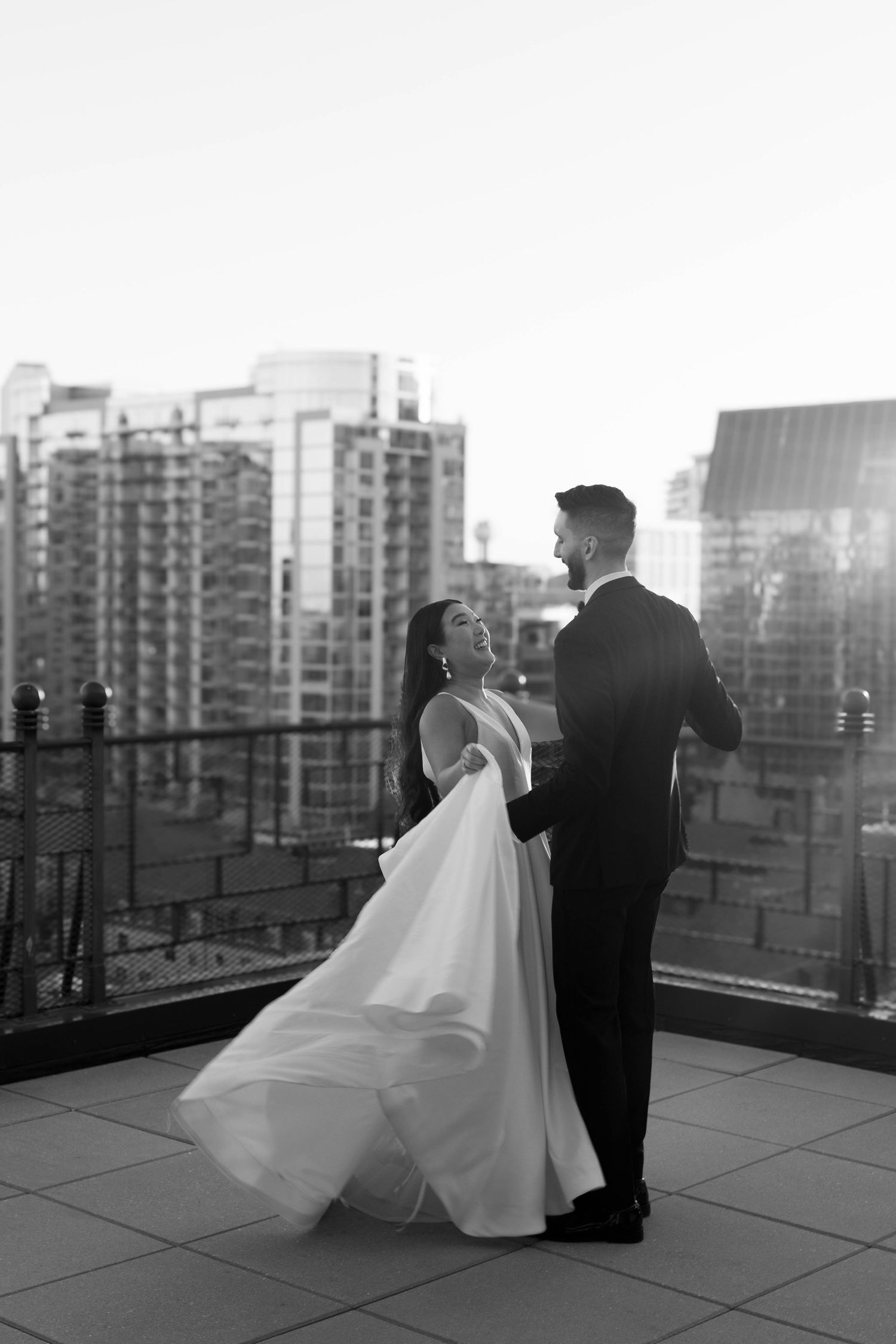 Romantic rooftop wedding photos with city skyline at dusk.