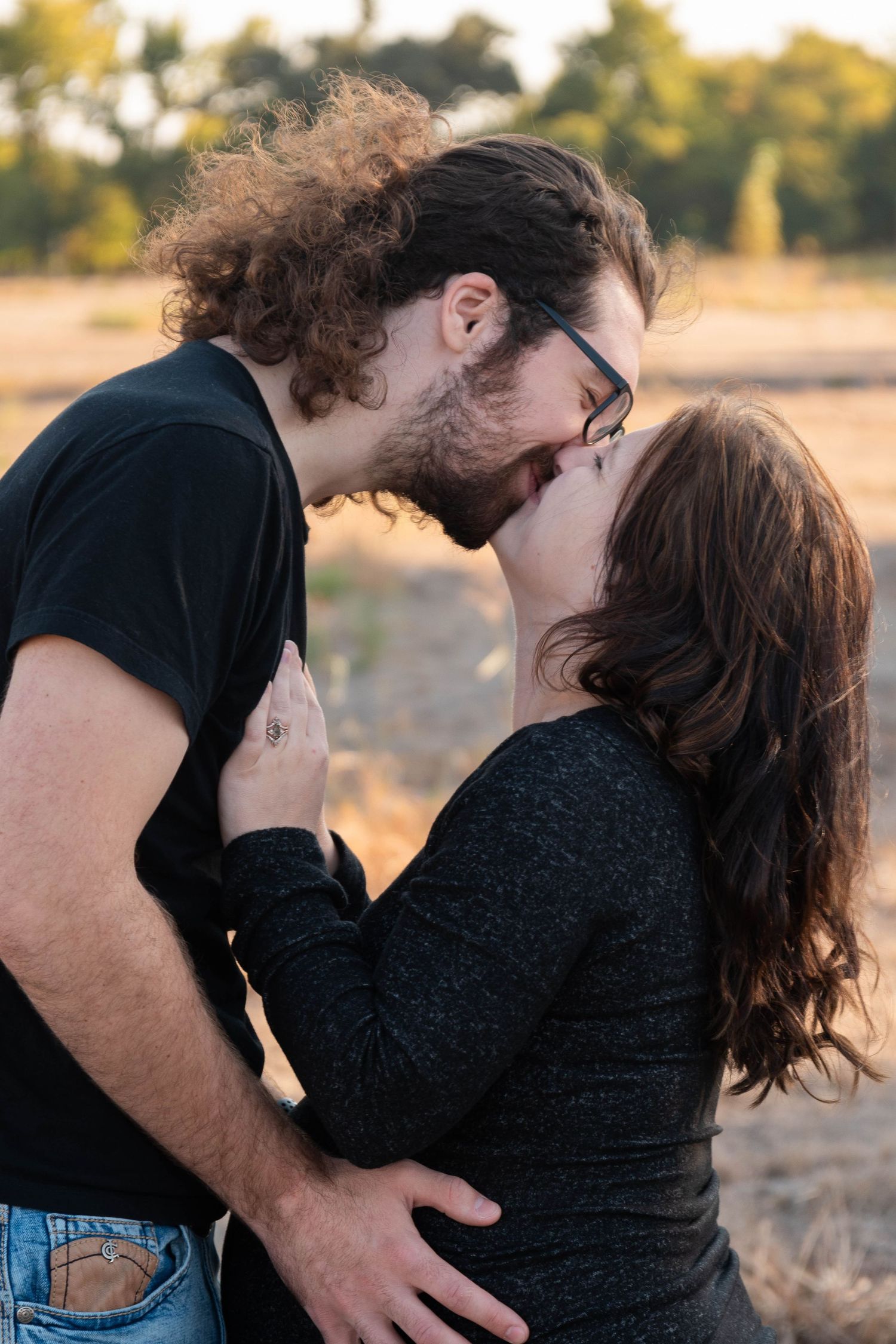 A romantic couple shares a tender moment in a golden field at sunset.