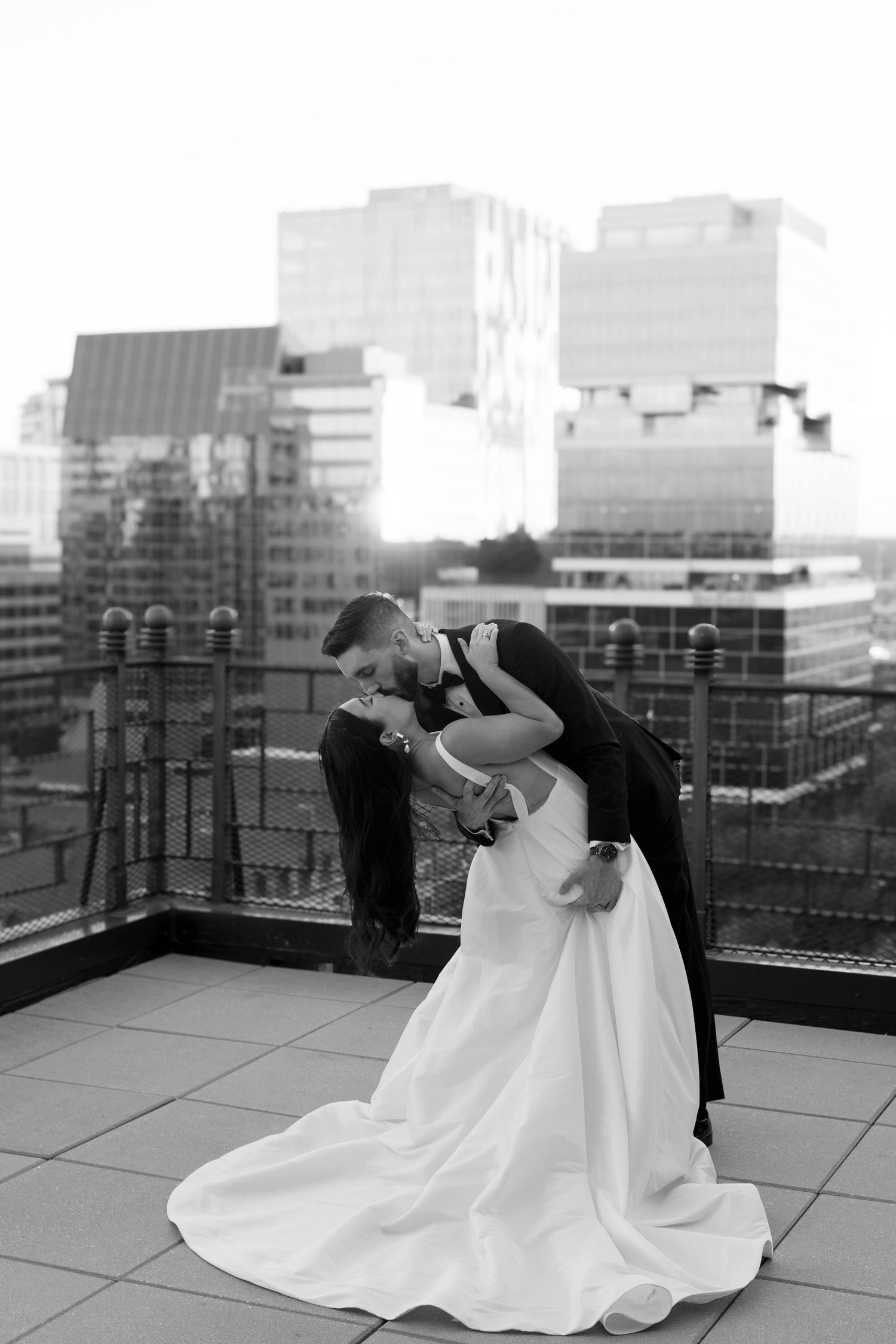 Black and white rooftop wedding portrait with city skyline backdrop.