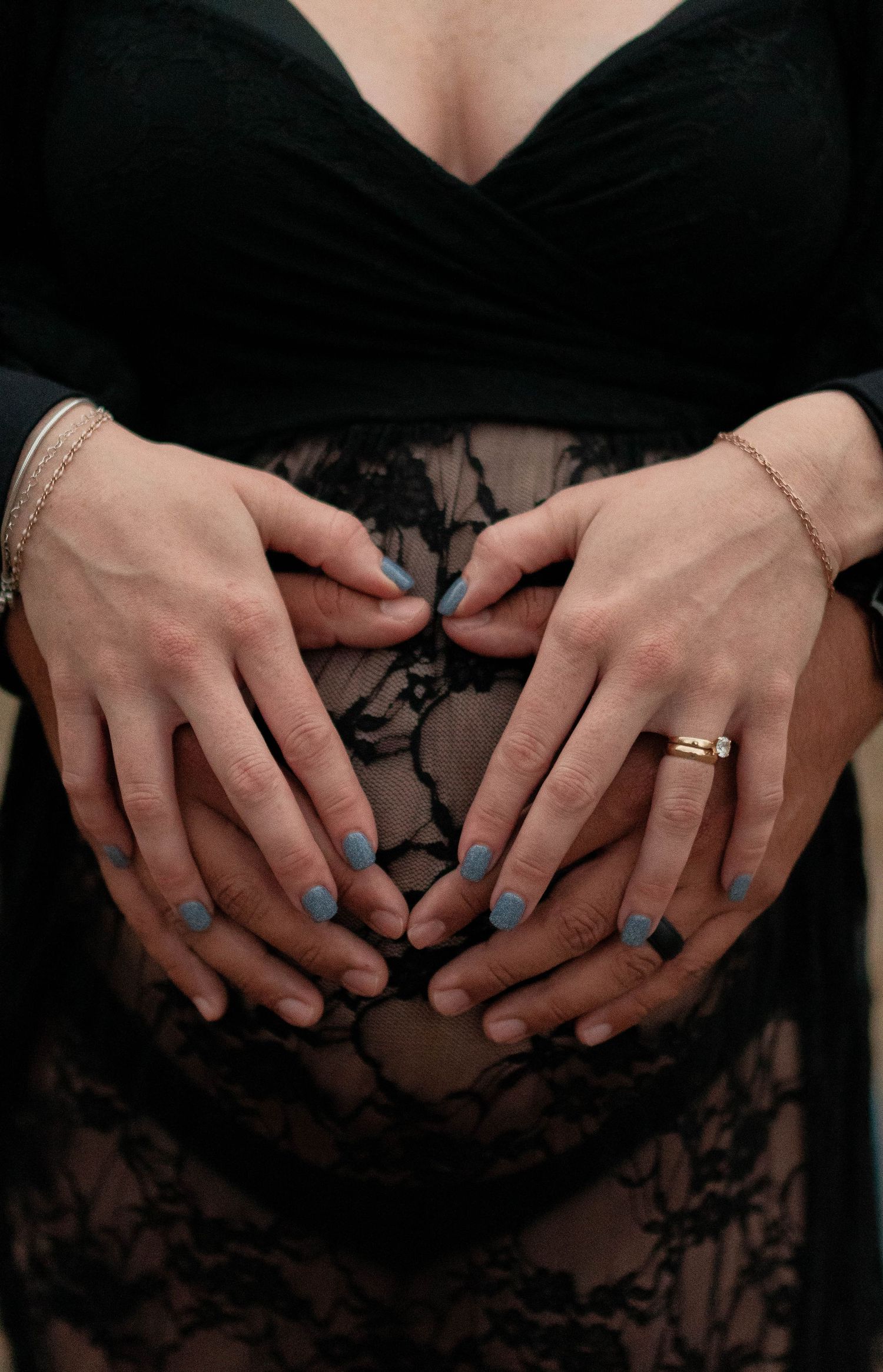 Close-up shots of hands with blue nail polish and wedding rings against a black lace background.