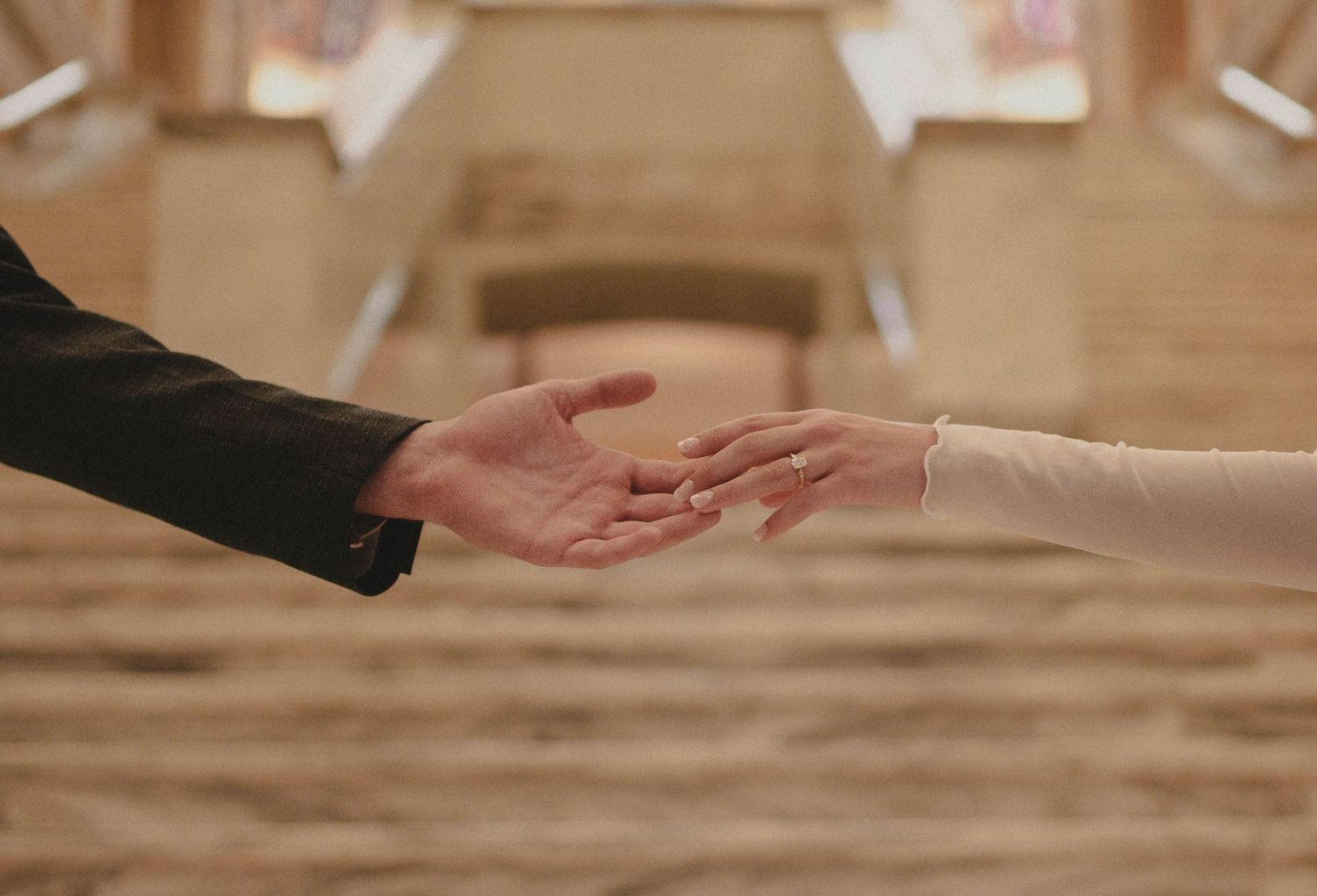 Two people reaching toward each other with open hands in an elegant church setting, symbolizing connection and unity.