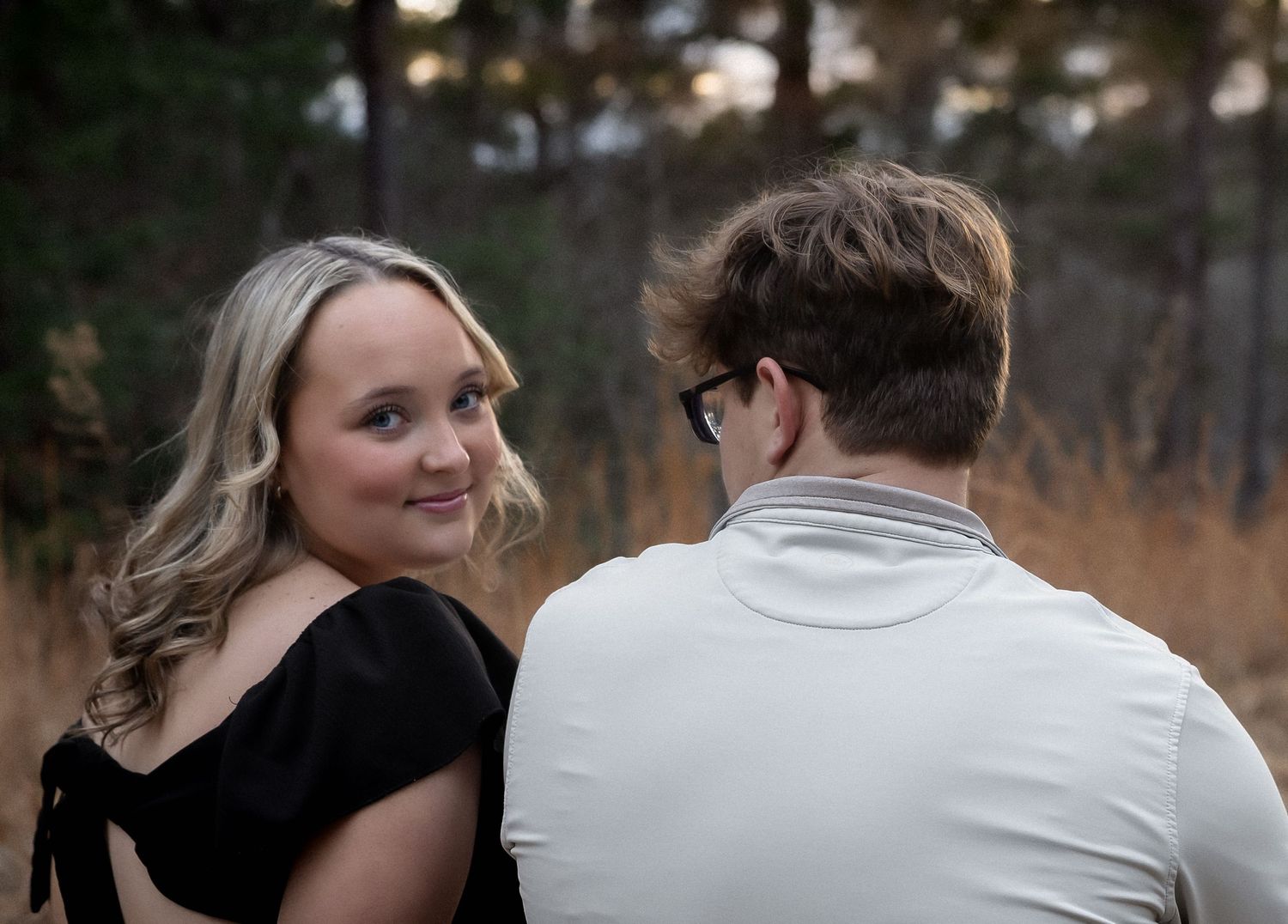 A couple embraces outdoors during a romantic autumn photoshoot with warm lighting and natural scenery.