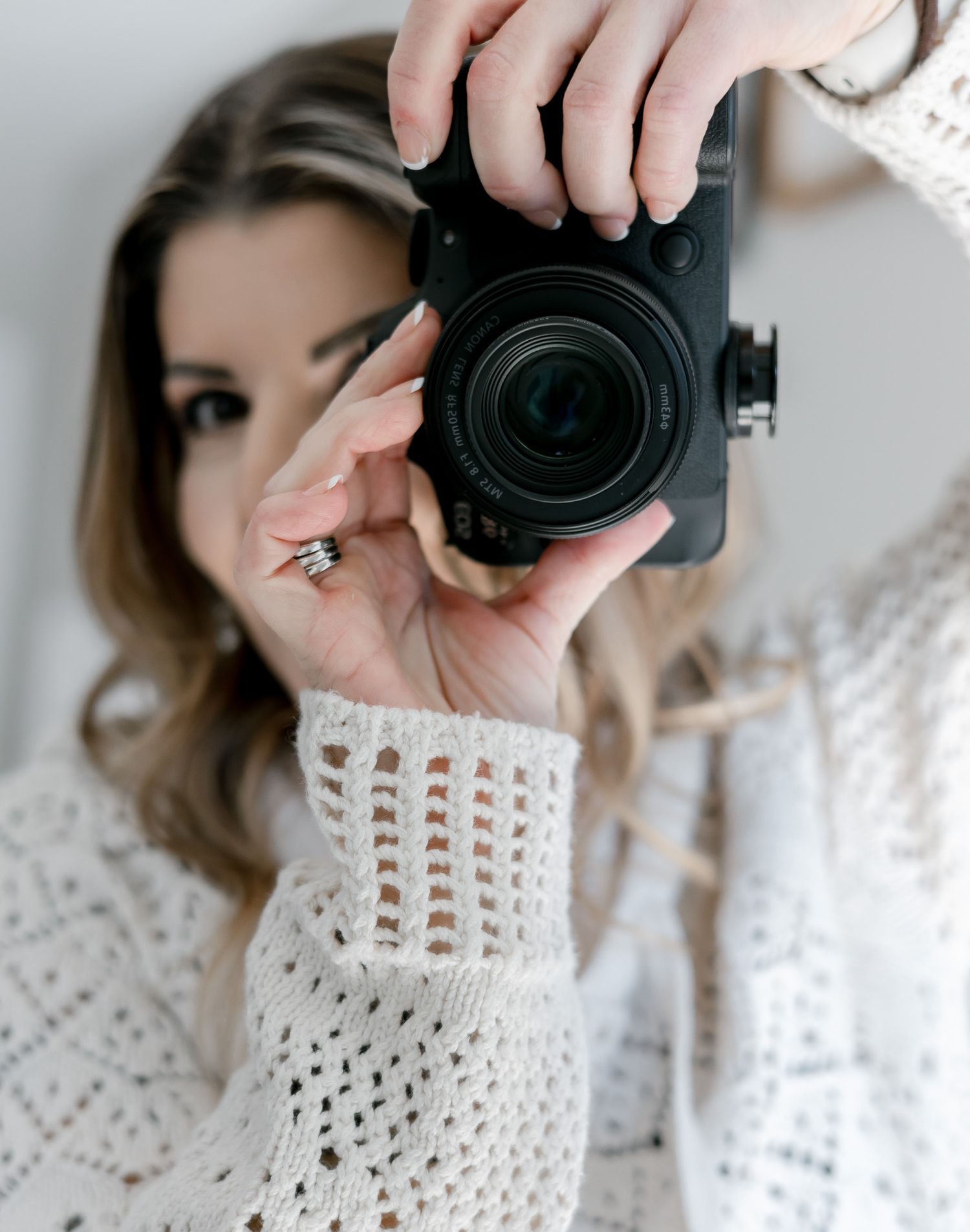 Close-up sequence of photographer with camera wearing white knit sweater.