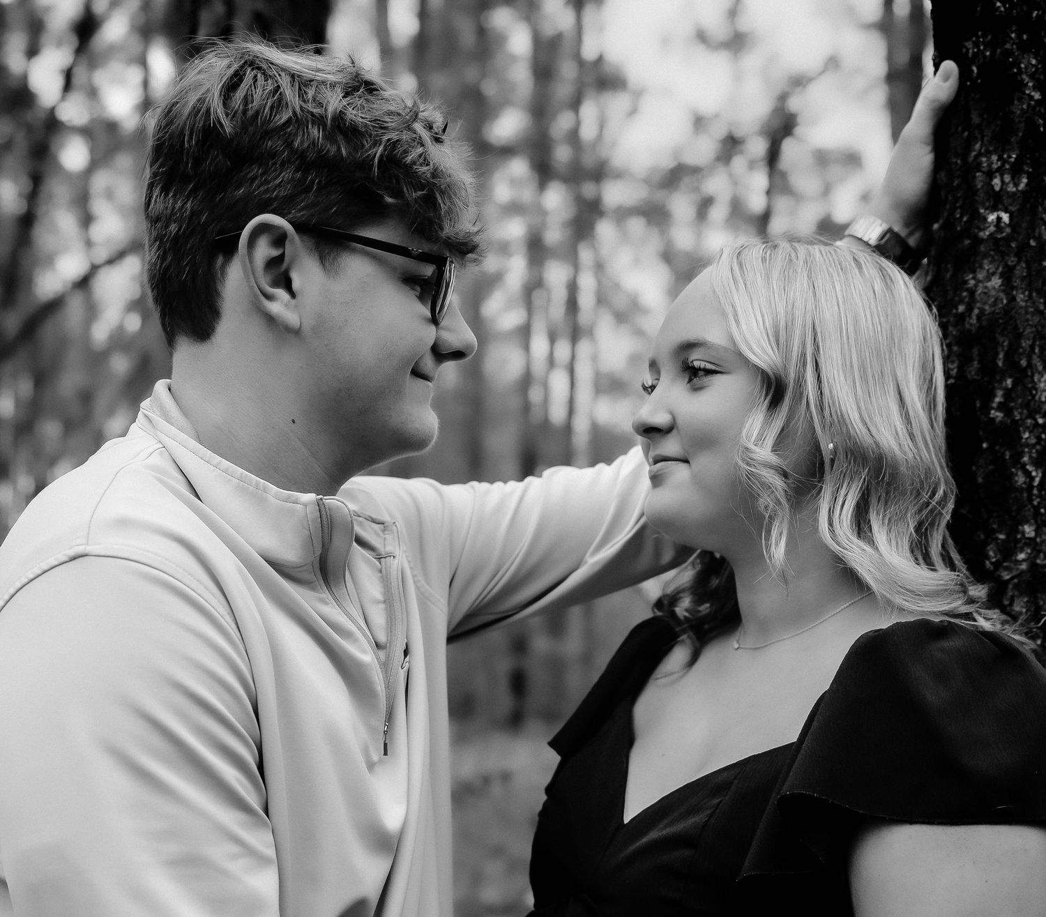 A black and white photo series showing a romantic couple sharing tender moments in a forest setting.
