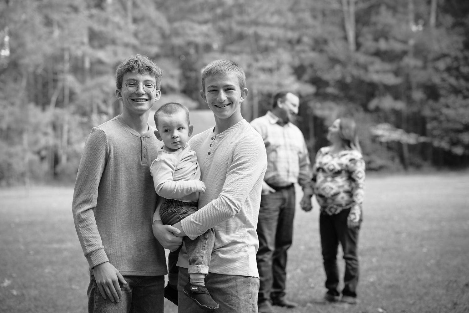 A collection of black and white candid photos showing joyful family moments in an outdoor setting.