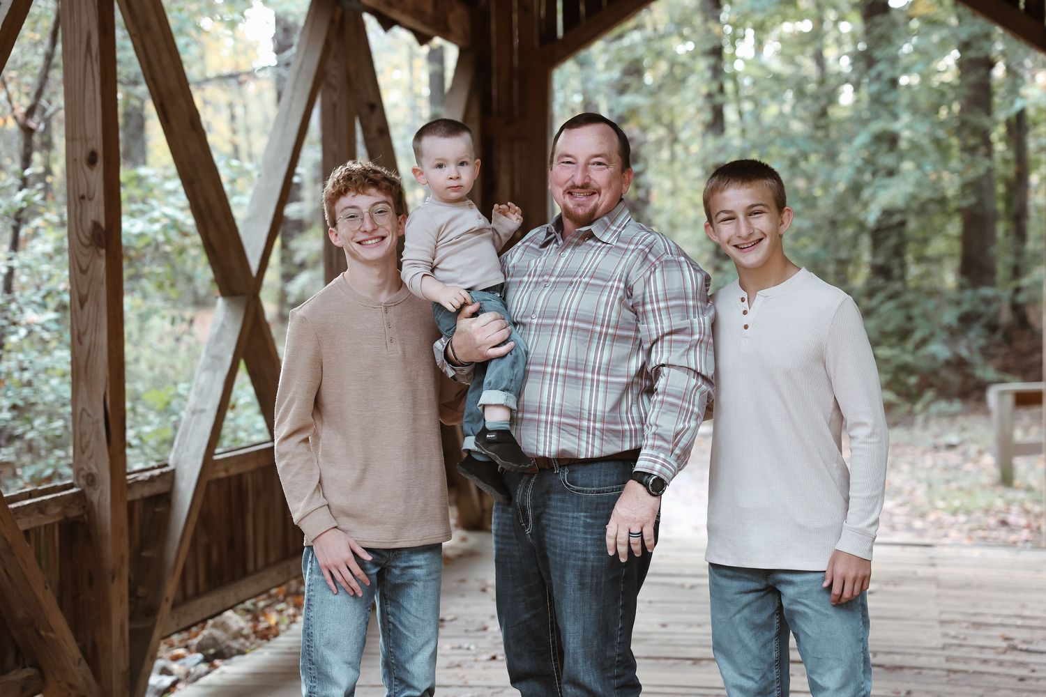 Group photo session in a rustic wooden covered bridge setting.