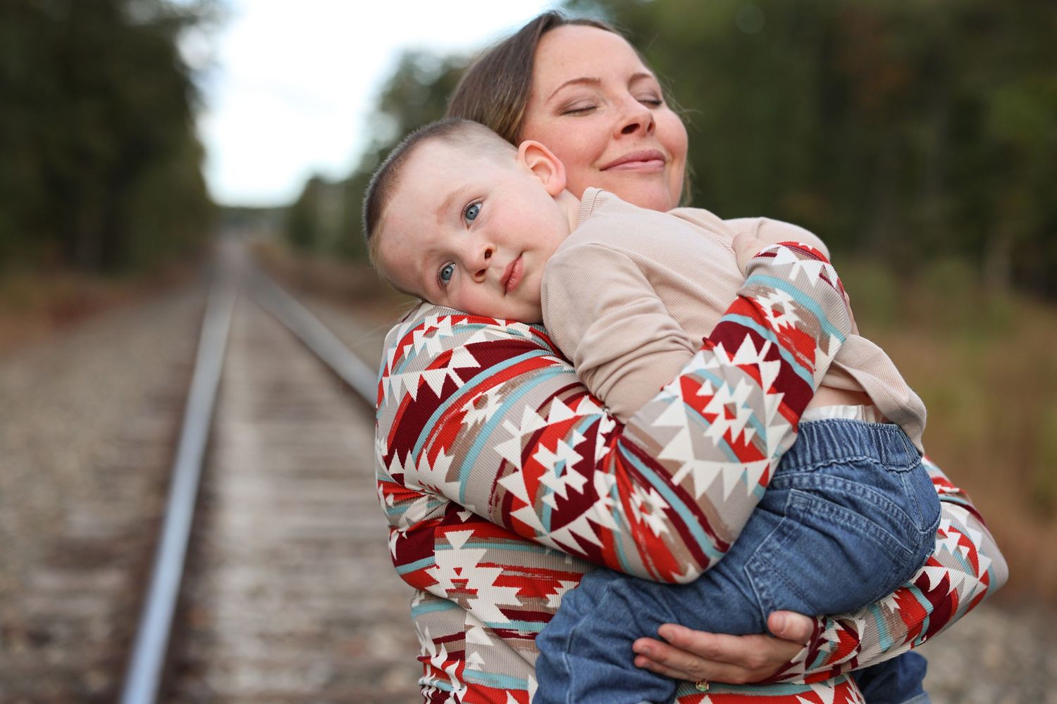 A series of candid outdoor photos showing tender moments between parent and child along railroad tracks.
