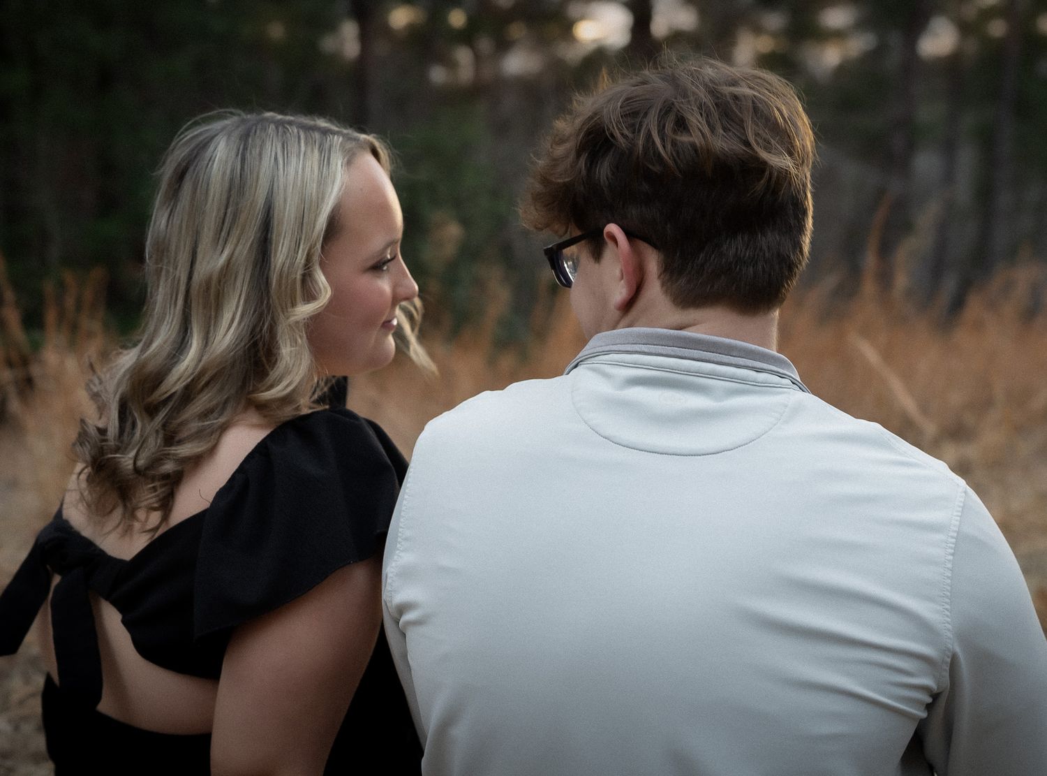 A couple embraces outdoors in a romantic pose during golden hour lighting.