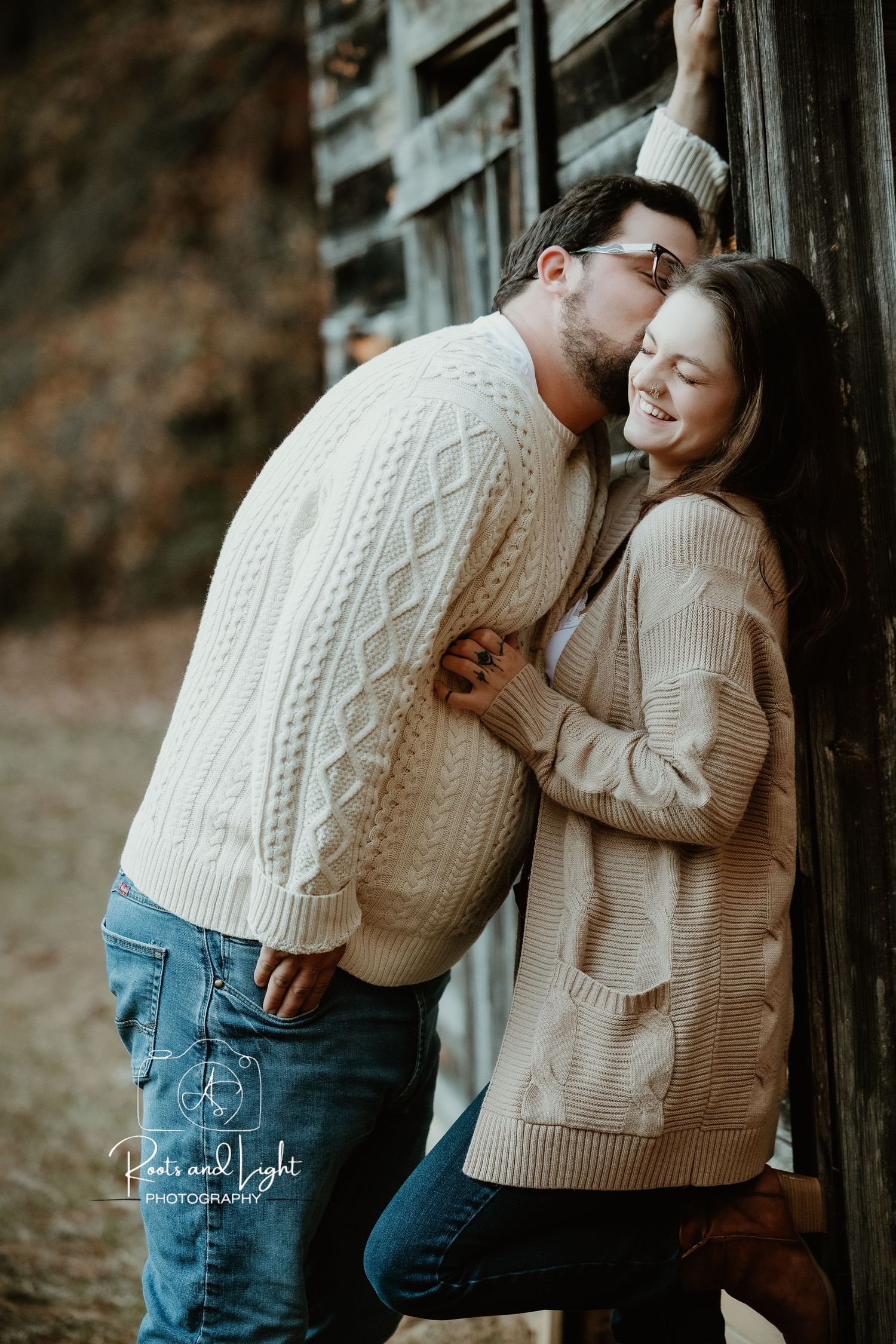 Couple in matching sweaters sharing intimate moments against wooden wall.