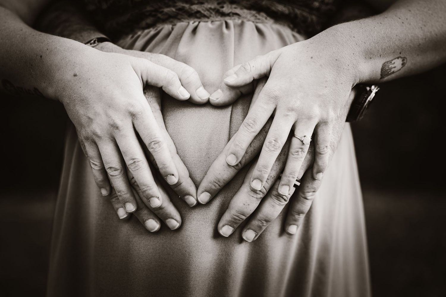 Close-up black and white detail of hands resting on fabric.