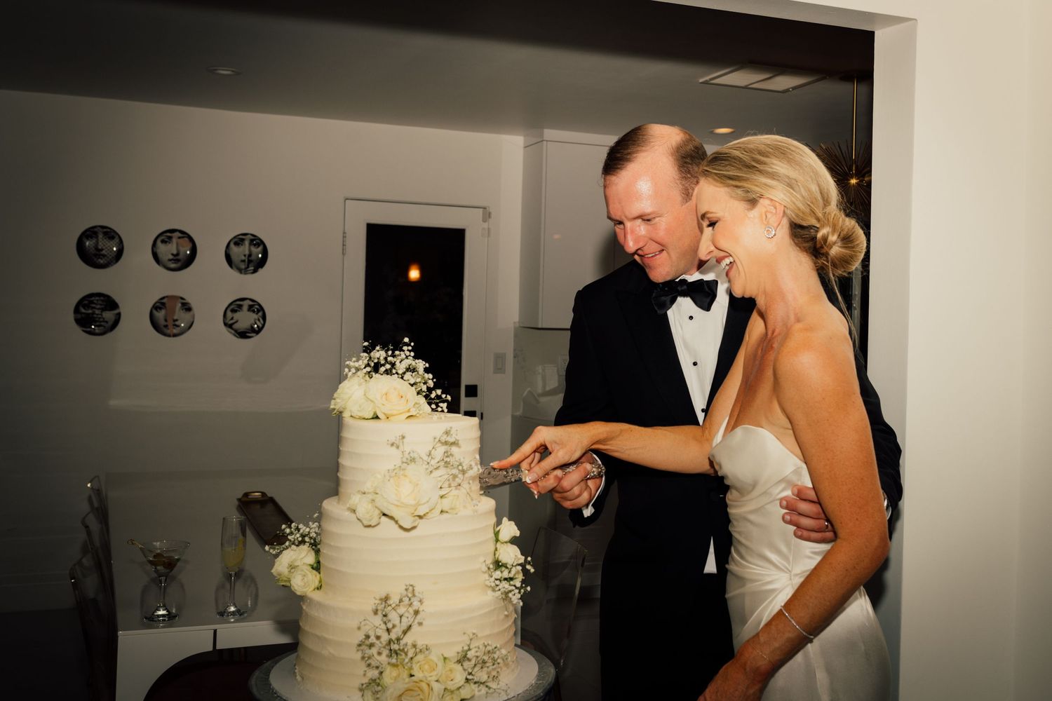 Louis Willard Photo Palm Springs Bride and groom cut their elegant white three-tier wedding cake adorned with delicate floral details.