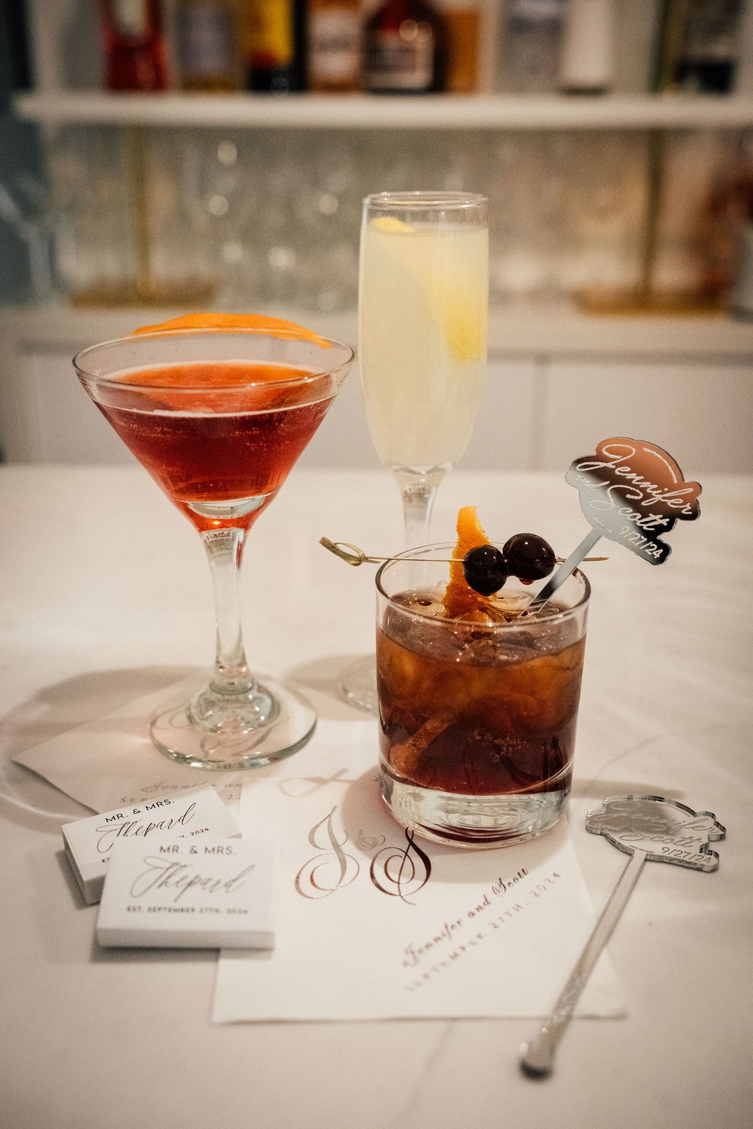Louis Willard Photo Palm Springs Three signature wedding cocktails displayed on white marble bar with custom cocktail napkins.