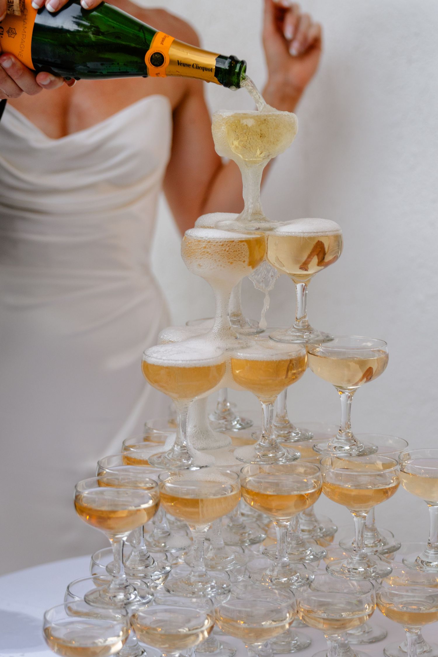 Louis Willard Photo Palm Springs Bride pours Veuve Clicquot champagne over tiered crystal coupe glass tower at wedding.