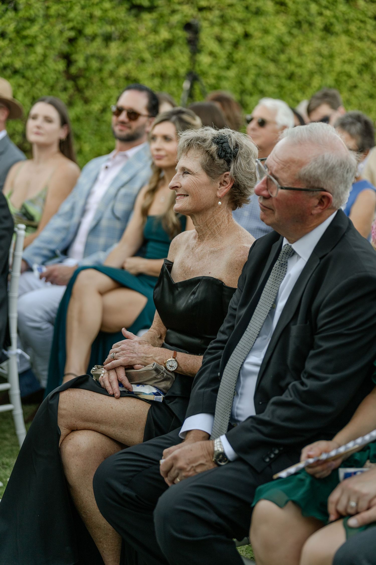 Louis Willard Photo Palm Springs Elegant wedding guests seated outdoors, older couple in formal attire watching ceremony.