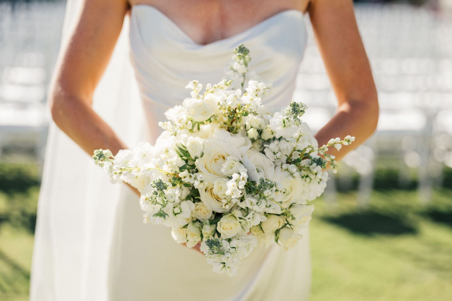 Louis Willard Photo Palm Springs Bride holds a lush white bouquet of roses and wildflowers against her elegant satin wedding gown.