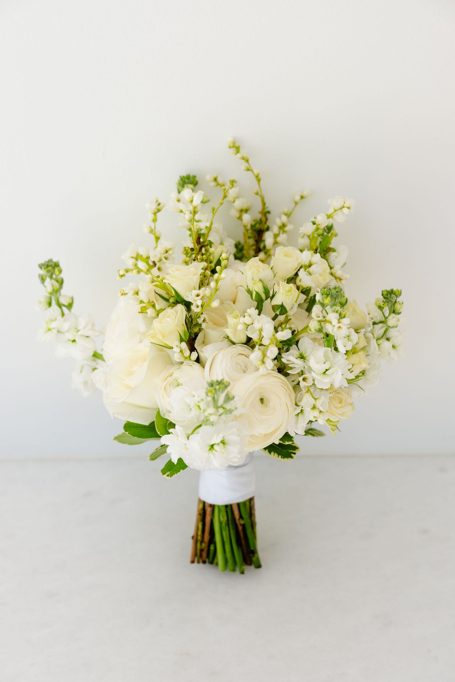 Louis Willard Photo Palm Springs Elegant white wedding bouquet with ranunculus and stock flowers.