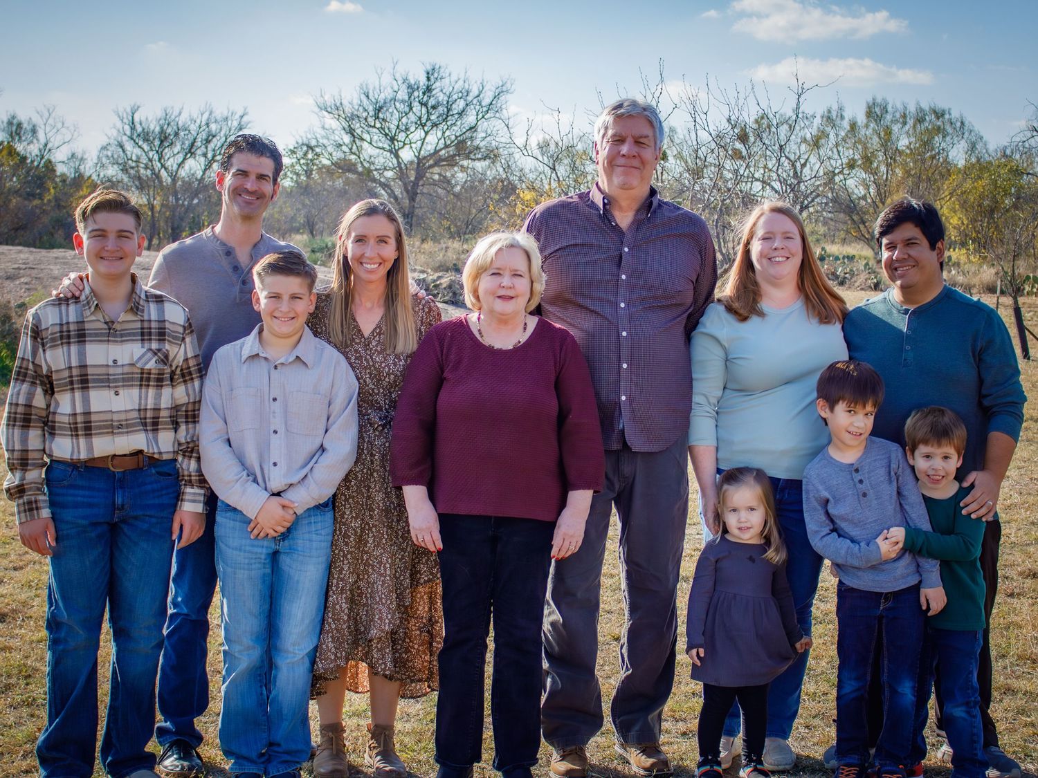 Extended family members gather for a group portrait in a scenic outdoor setting.