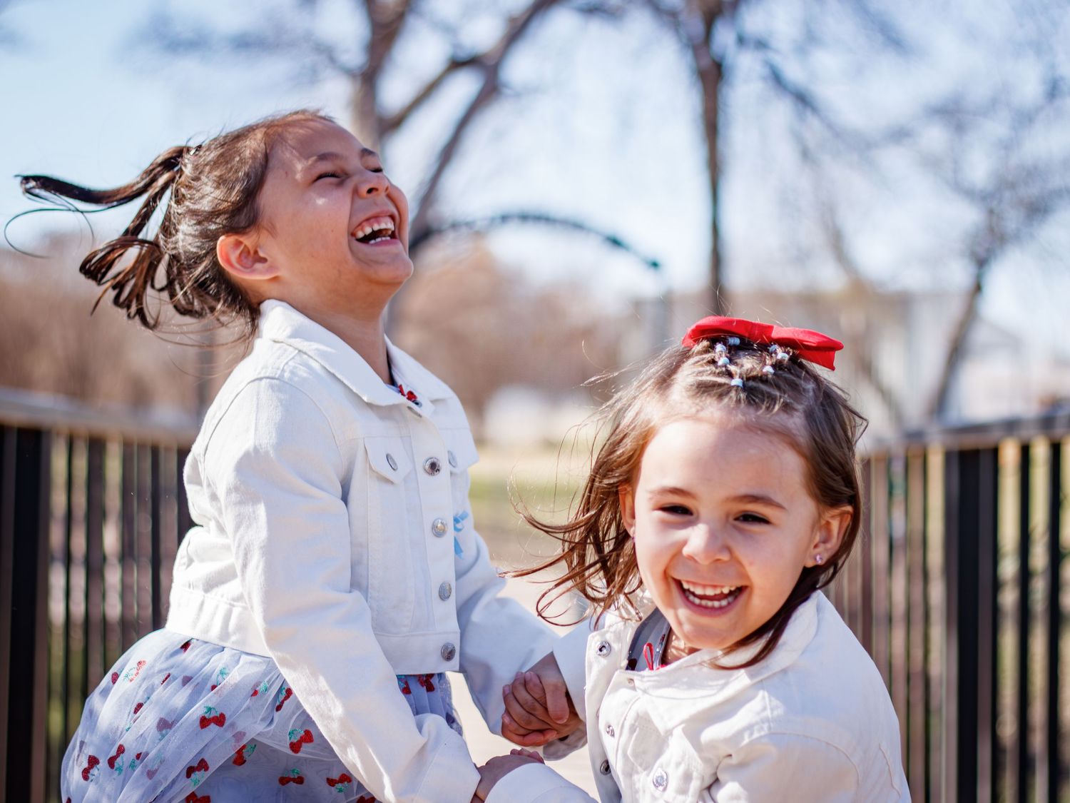 Candid outdoor photo of children playing and laughing together in white outfits.