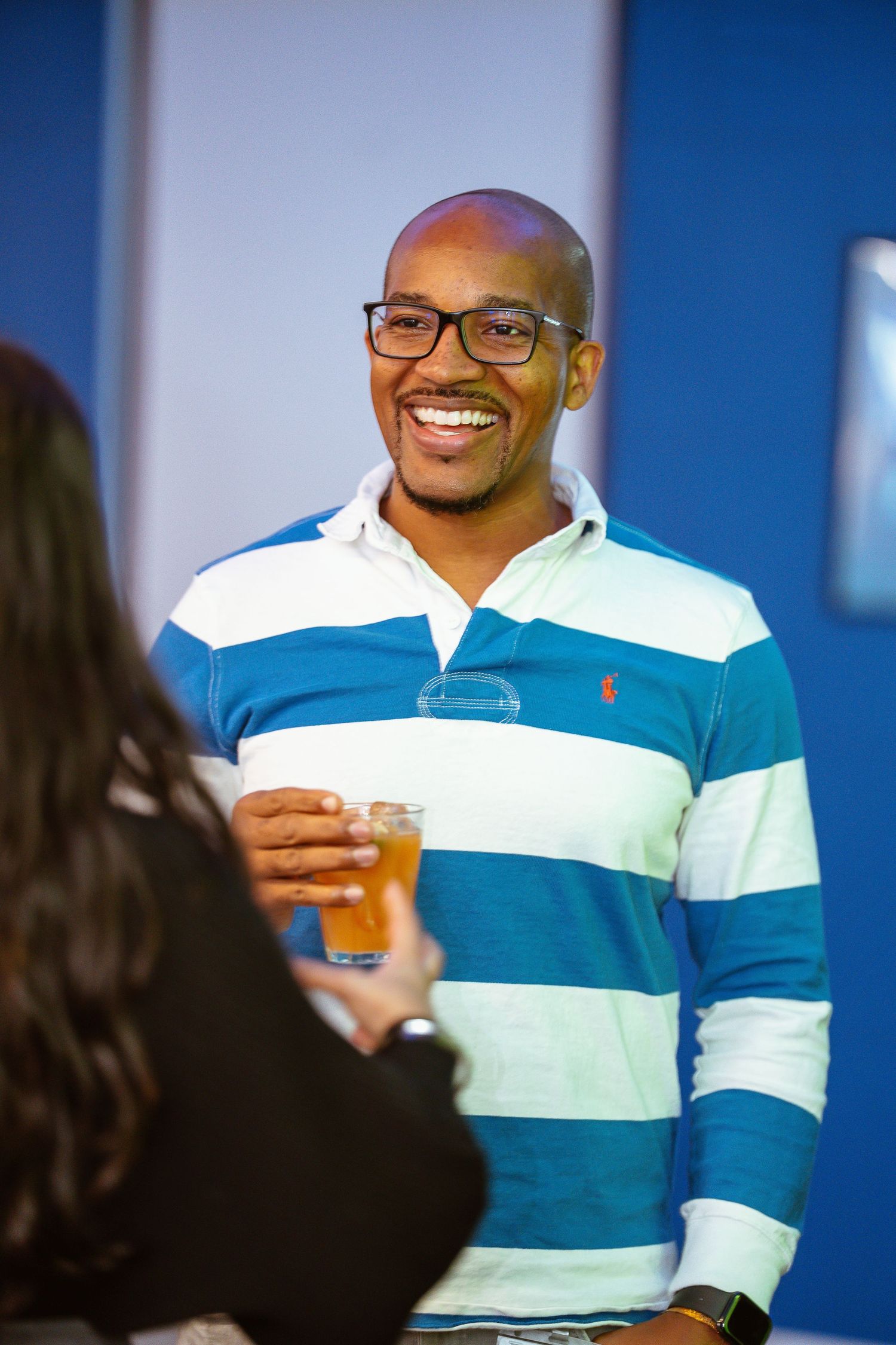Person in a blue and white striped polo shirt smiling during a conversation.