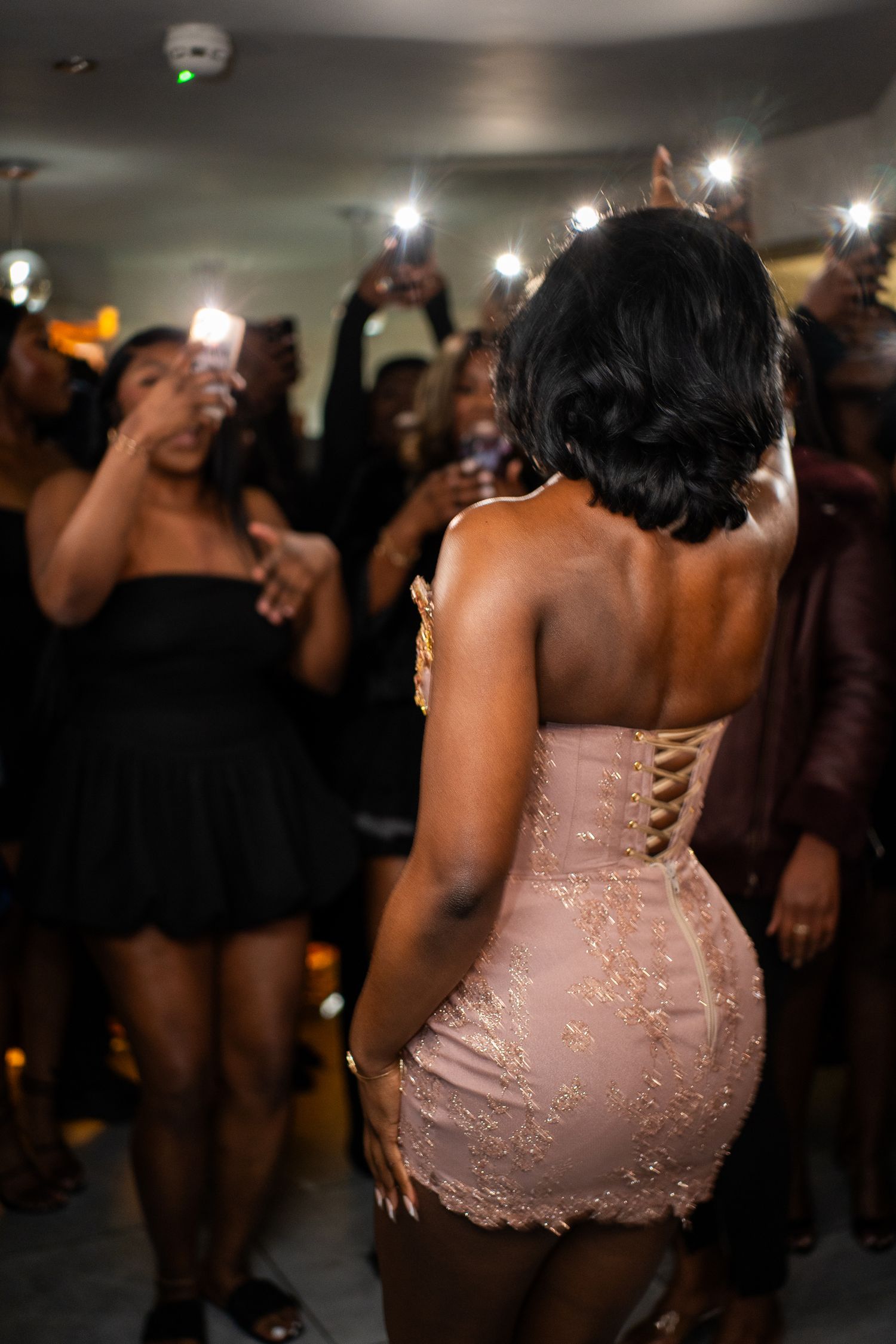 Person wearing a sparkly pink strapless dress dancing at a dimly lit party.