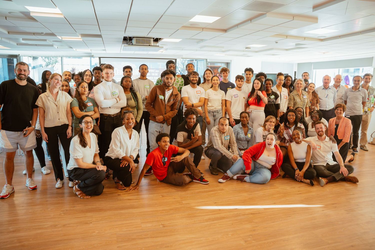 Large group of diverse people posing together in a bright studio space.