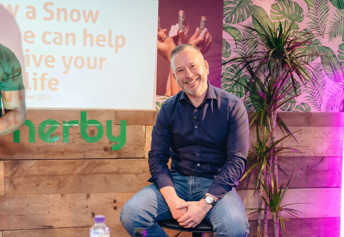 Conference or panel discussion setup with plants and wooden backdrop.