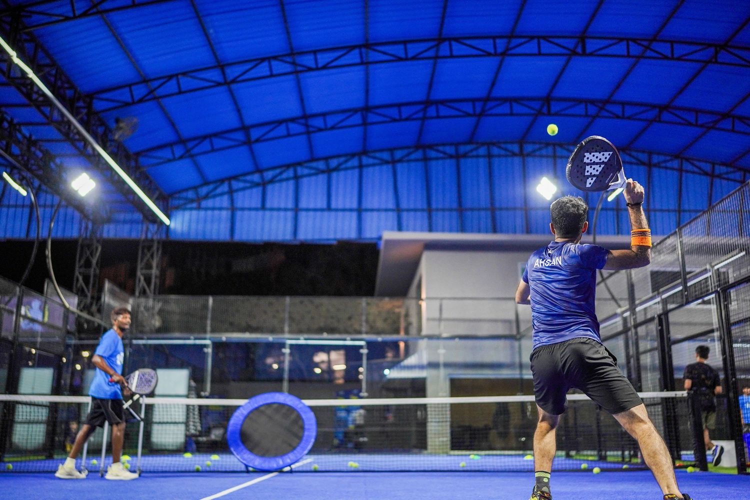 Wide shot of padel court with players.