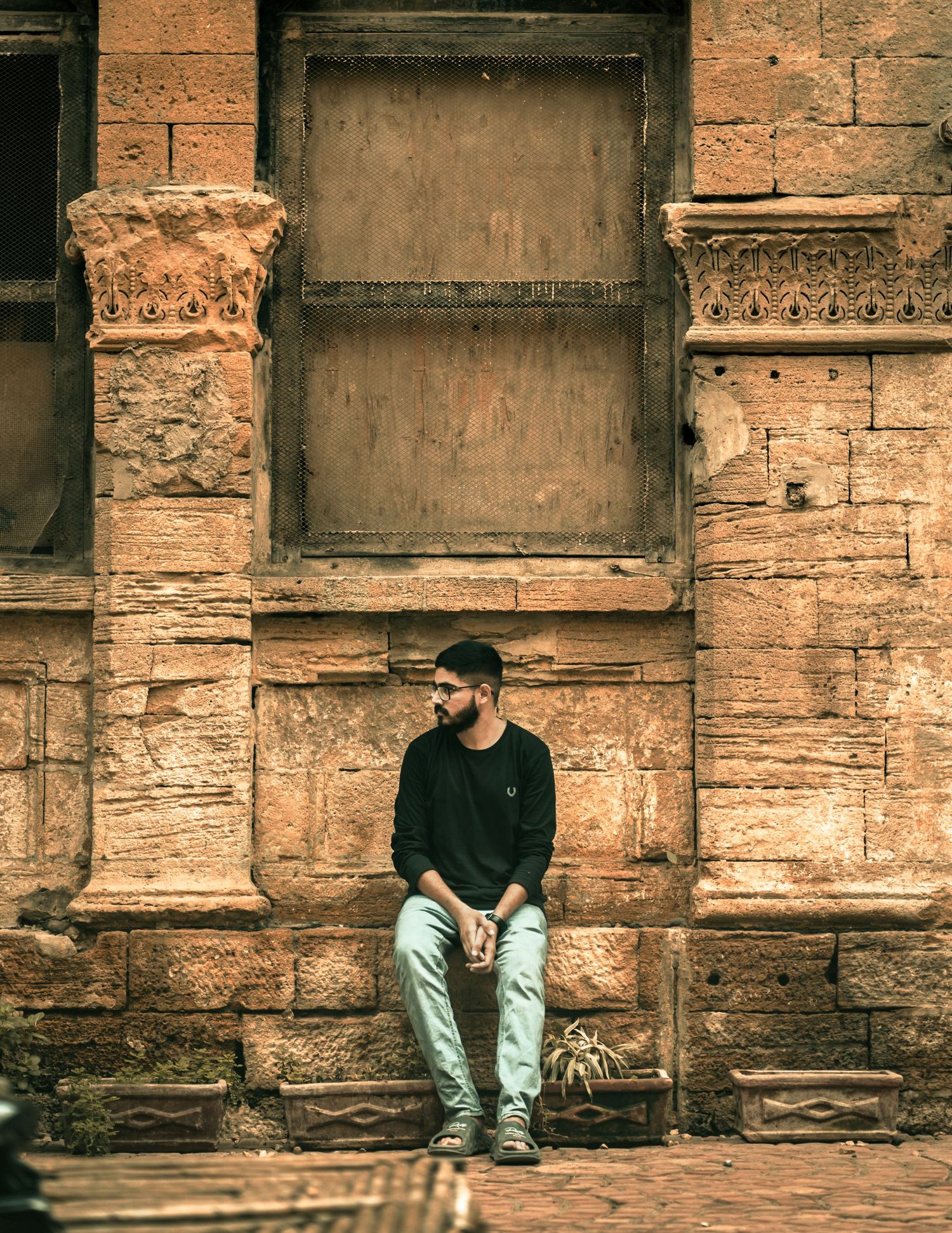 A man sitting outside of old building in Karachi.