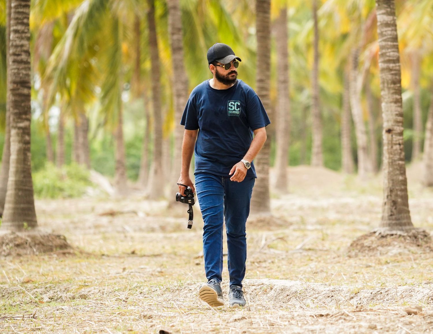 A boy walking in the woods holding a camera.