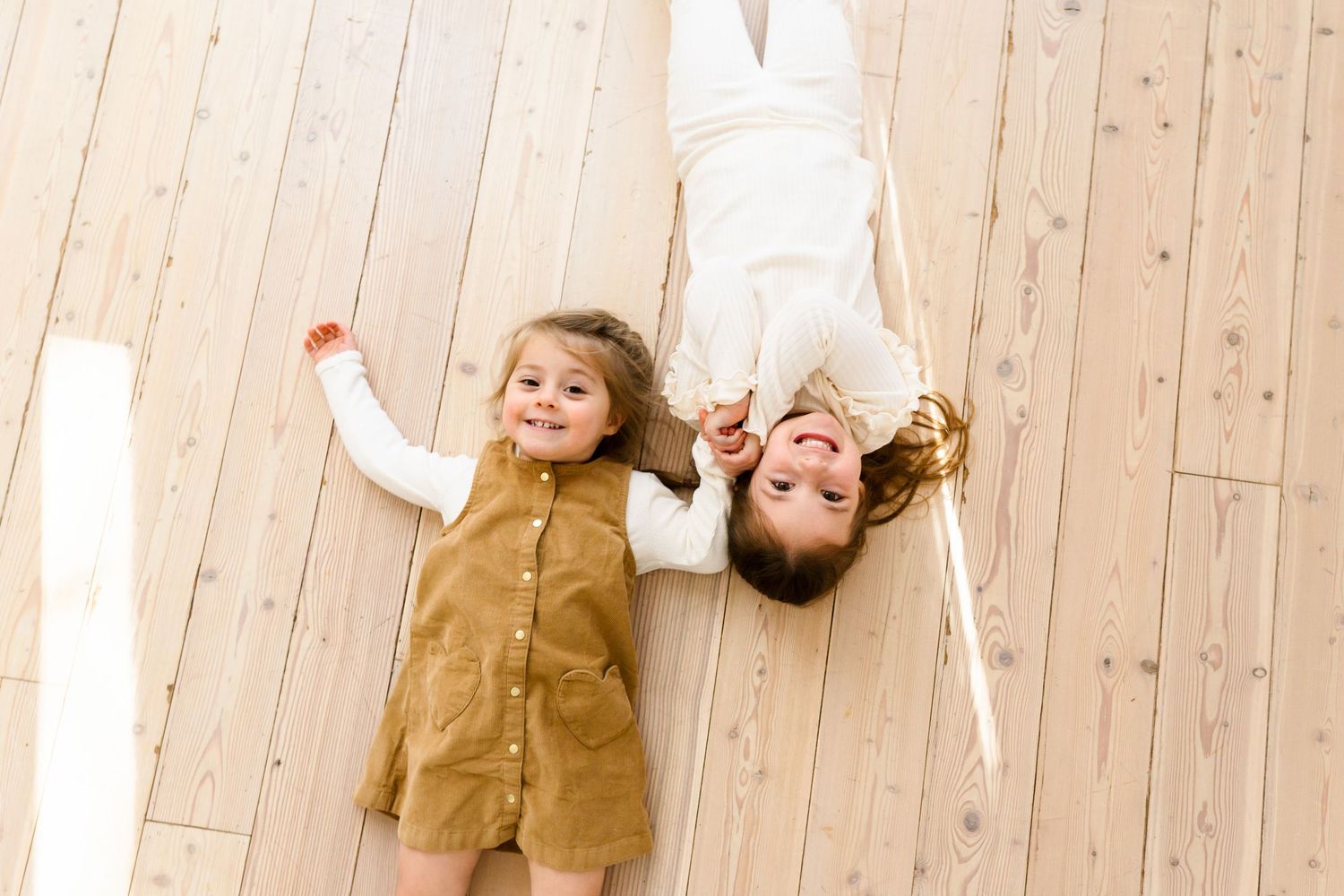 Joyful interactions photographed on light wooden floors in a minimalist setting.