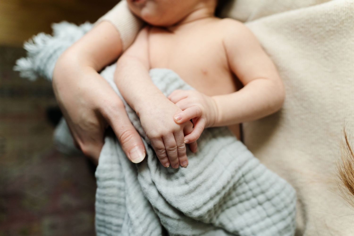 Gentle hands caressing a baby wearing soft muslin fabric.